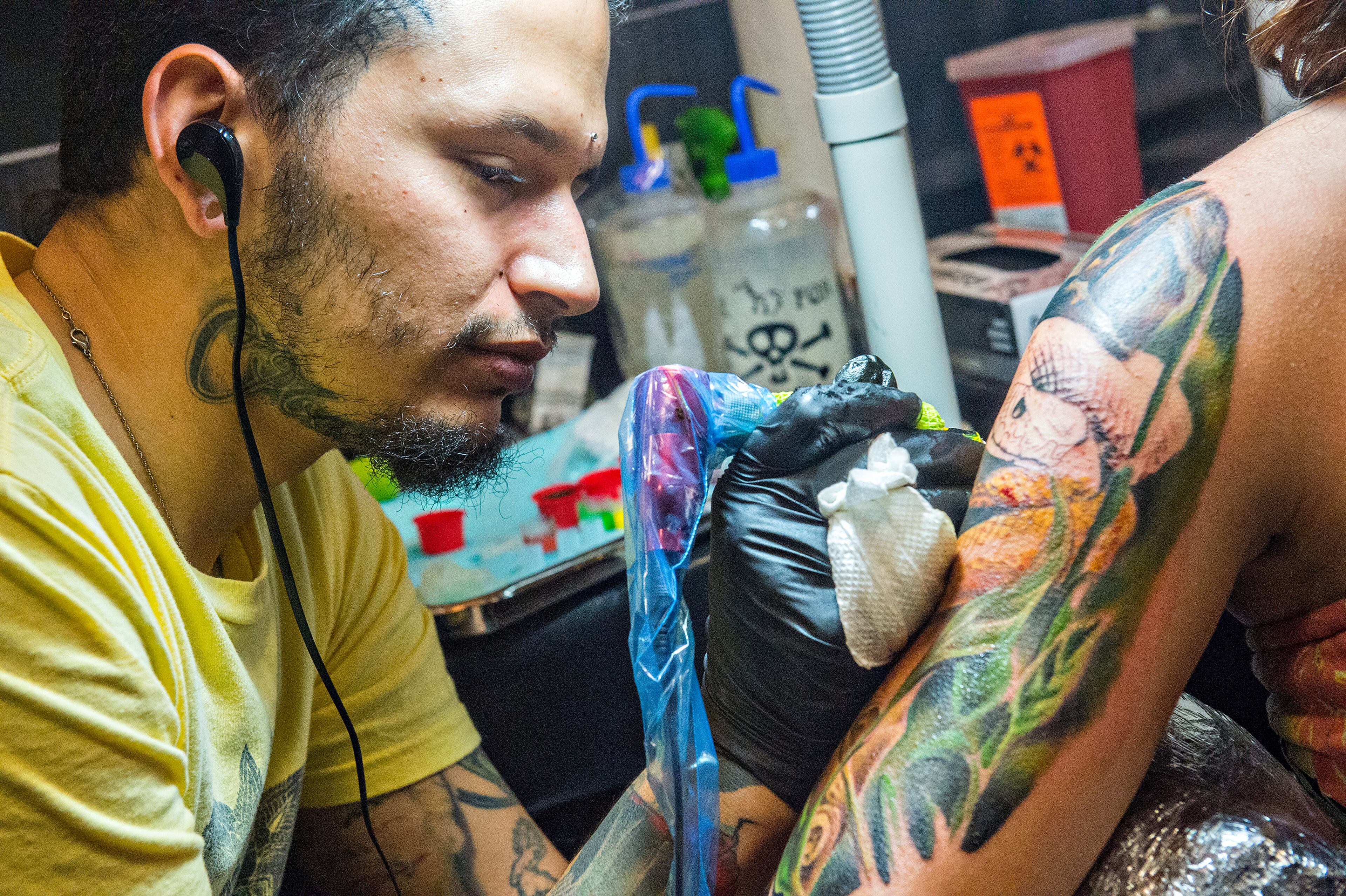 June 20, 2015 Atlanta - Oscar Zornosa (left) adds color to a snake tattoo for Jordan Galehan during the 19th annual Atlanta Tattoo Expo at the Wyndham Atlanta Galleria hotel on Saturday, June 20, 2015. Around 100 tattoo artists from across the country were booked solid throughout the three day event as hundreds of people came out to watch and get tattooed. JONATHAN PHILLIPS / SPECIAL