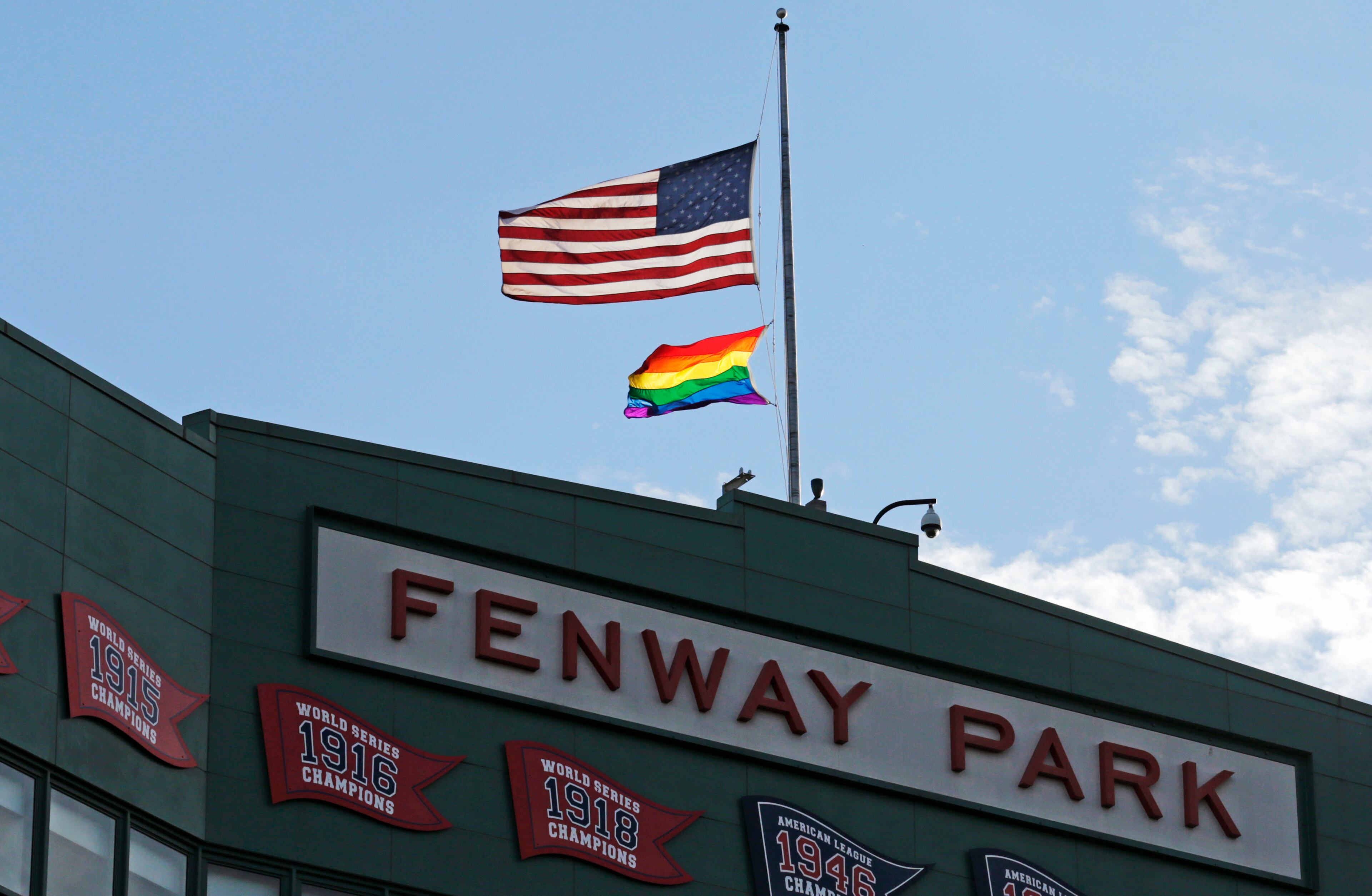 American and gay pride flags fly at half-staff in honor to the victims in the Orlando night club shooting prior to the first inning of a baseball game between the Baltimore Orioles and Boston Red Sox at Fenway Park, Tuesday, June 14, 2016, in Boston. (AP Photo/Charles Krupa)