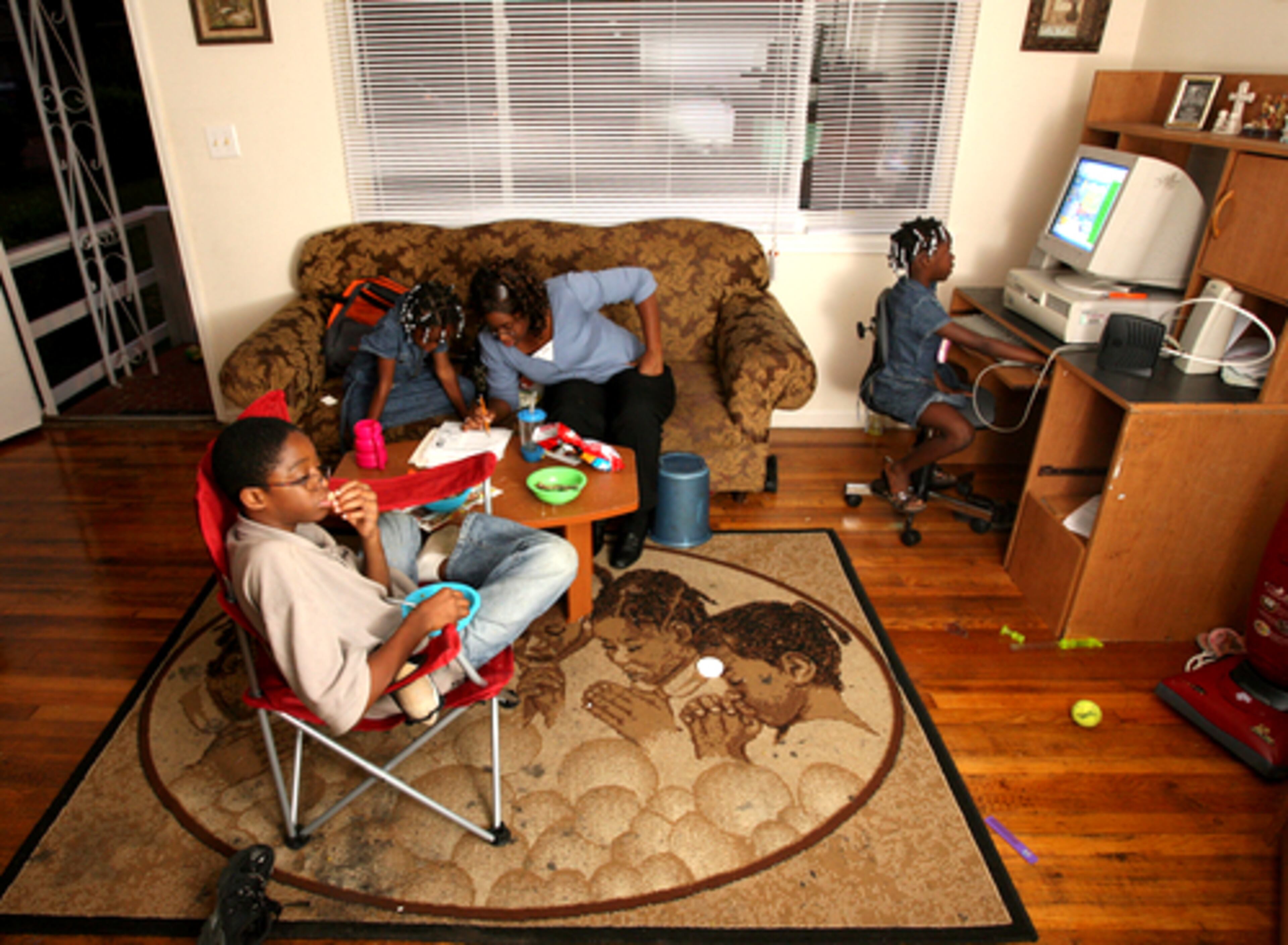 Lillian Hollis helps her daughter Carneshia, 8, with homework as her son Marcus, 11, eats dinner and watches T.V. and daughter Dayonica, 7, plays on the computer. Hollis found a home in the Thomasville neighborhood of Atlanta.
