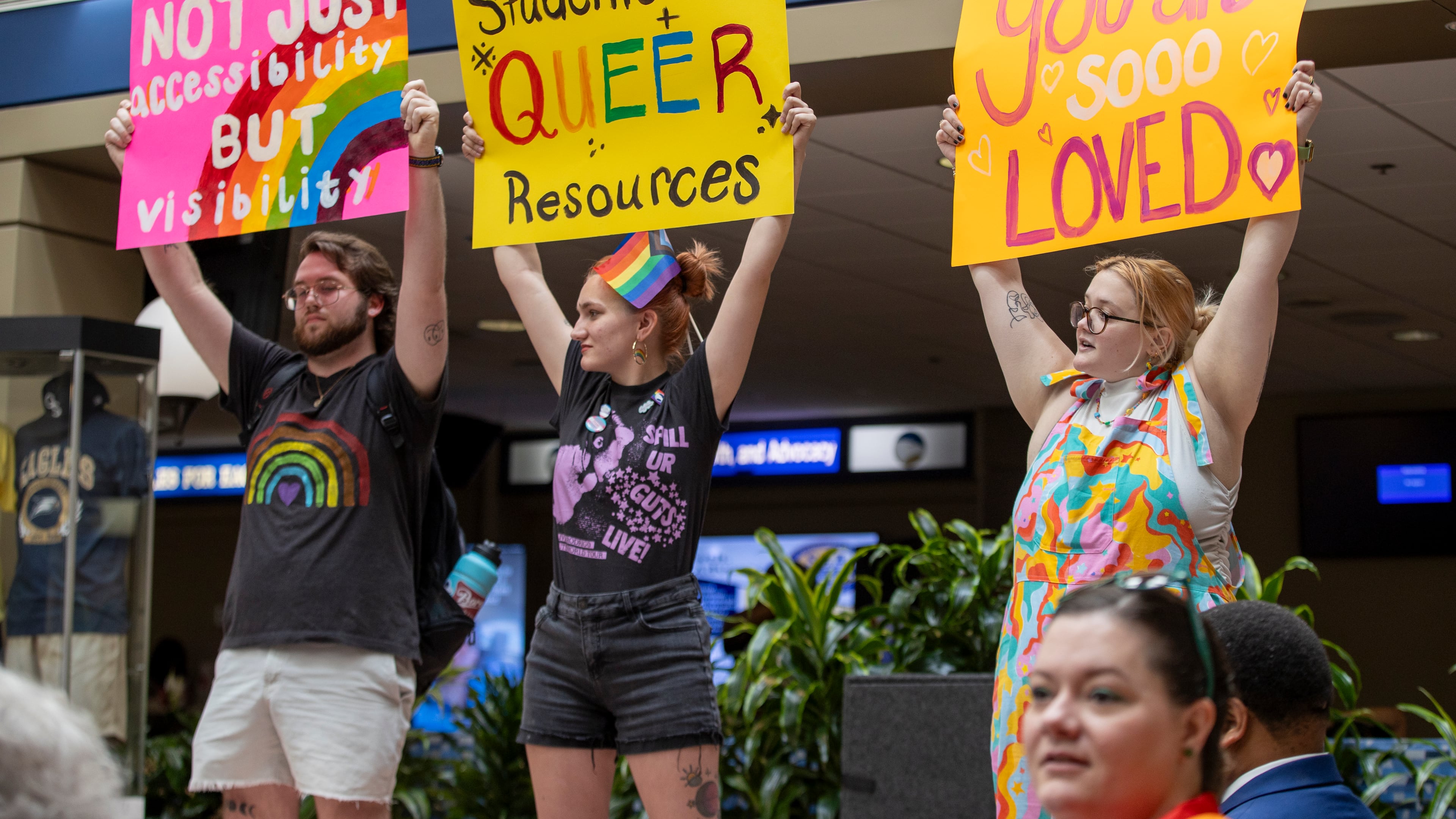 Seth Lee, Bo Bowman and Gracie Lee hold up signs during a protest LGBTQ students at Georgia Southern University held Monday. The peaceful protest was in response to moves the university's leadership recently made involving health care and inclusion on the campus in Statesboro. (AJC Photo/Katelyn Myrick)