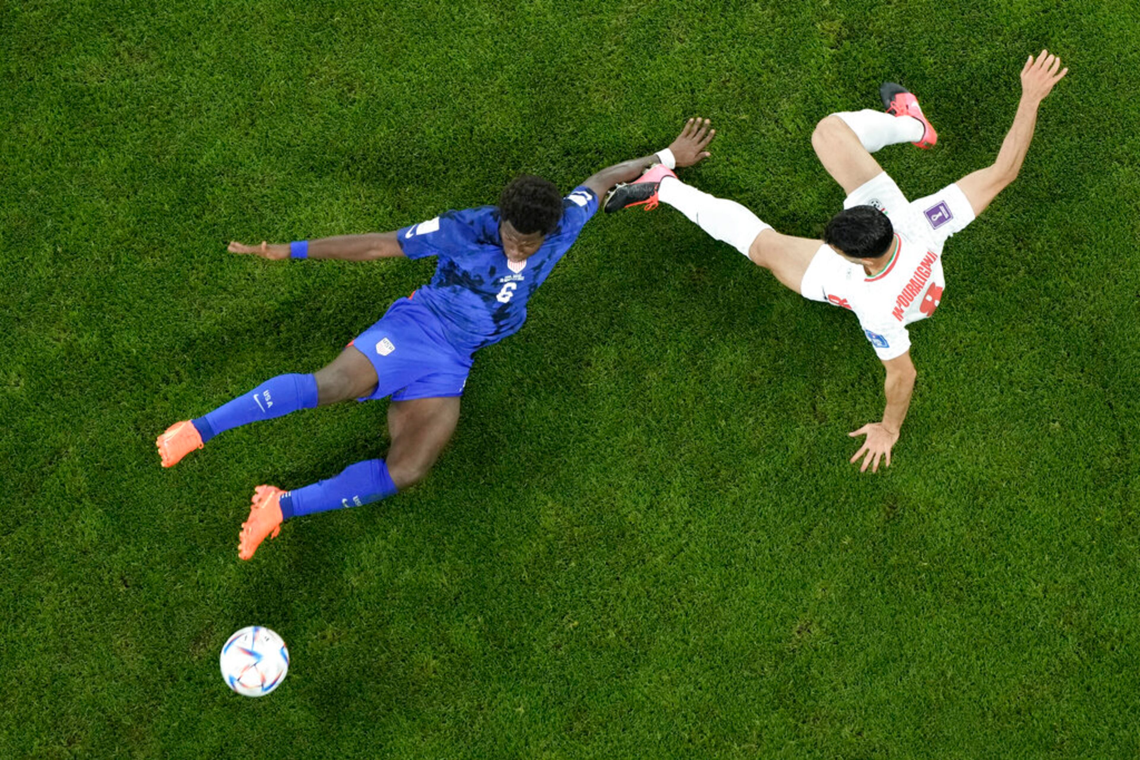 Yunus Musah of the United States tries to block a shot from Iran's Morteza Pouraliganji, right, during the World Cup group B soccer match between Iran and the United States at the Al Thumama Stadium in Doha, Qatar, Tuesday, Nov. 29, 2022. (AP Photo/Hassan Ammar)