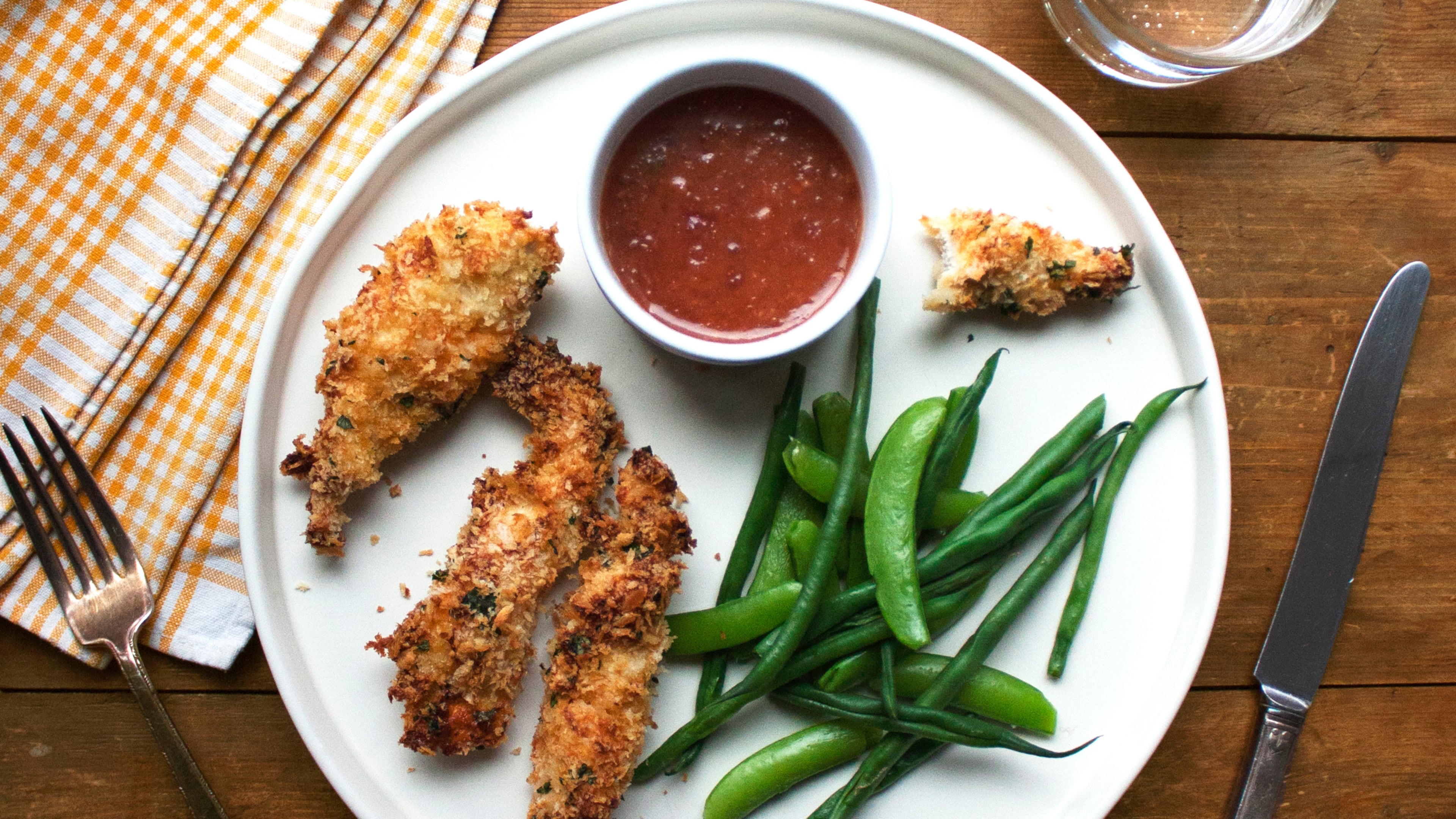 This image shows a recipe for crispy chicken strips with an apricot mustard dipping sauce. (Katie Workman via AP)