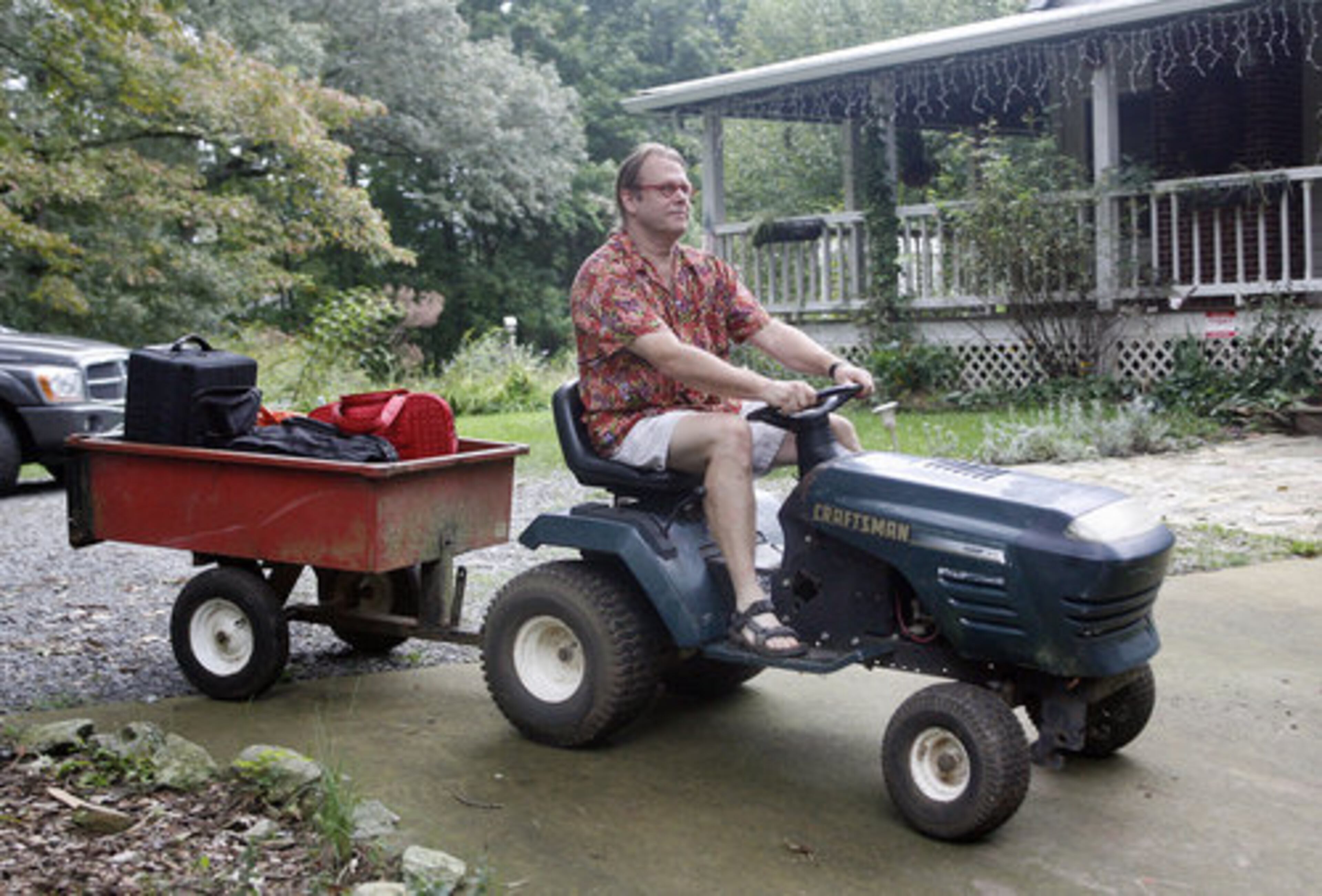 Co-owner Rick Lucas loads guests' luggage on a trailer and heads towards the woods on his lawn mower.