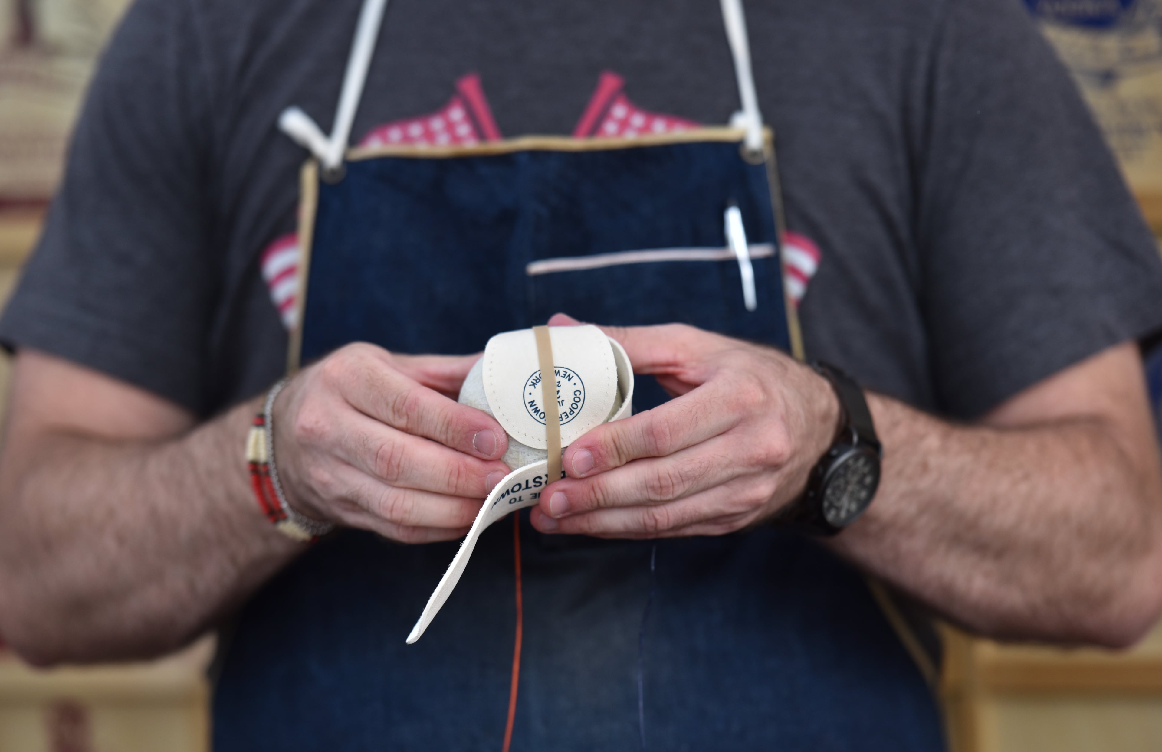 July 28, 2018 Cooperstown, N.Y. - William Peebles, owner of Huntington Baseball Co., is making a handmade baseball as visitors walk by on Main Street in Cooperstown, N.Y. on Saturday, July 28, 2018. Braves legend Chipper Jones is set for induction into the National Baseball Hall of Fame on Sunday in Cooperstown, N.Y. HYOSUB SHIN / HSHIN@AJC.COM