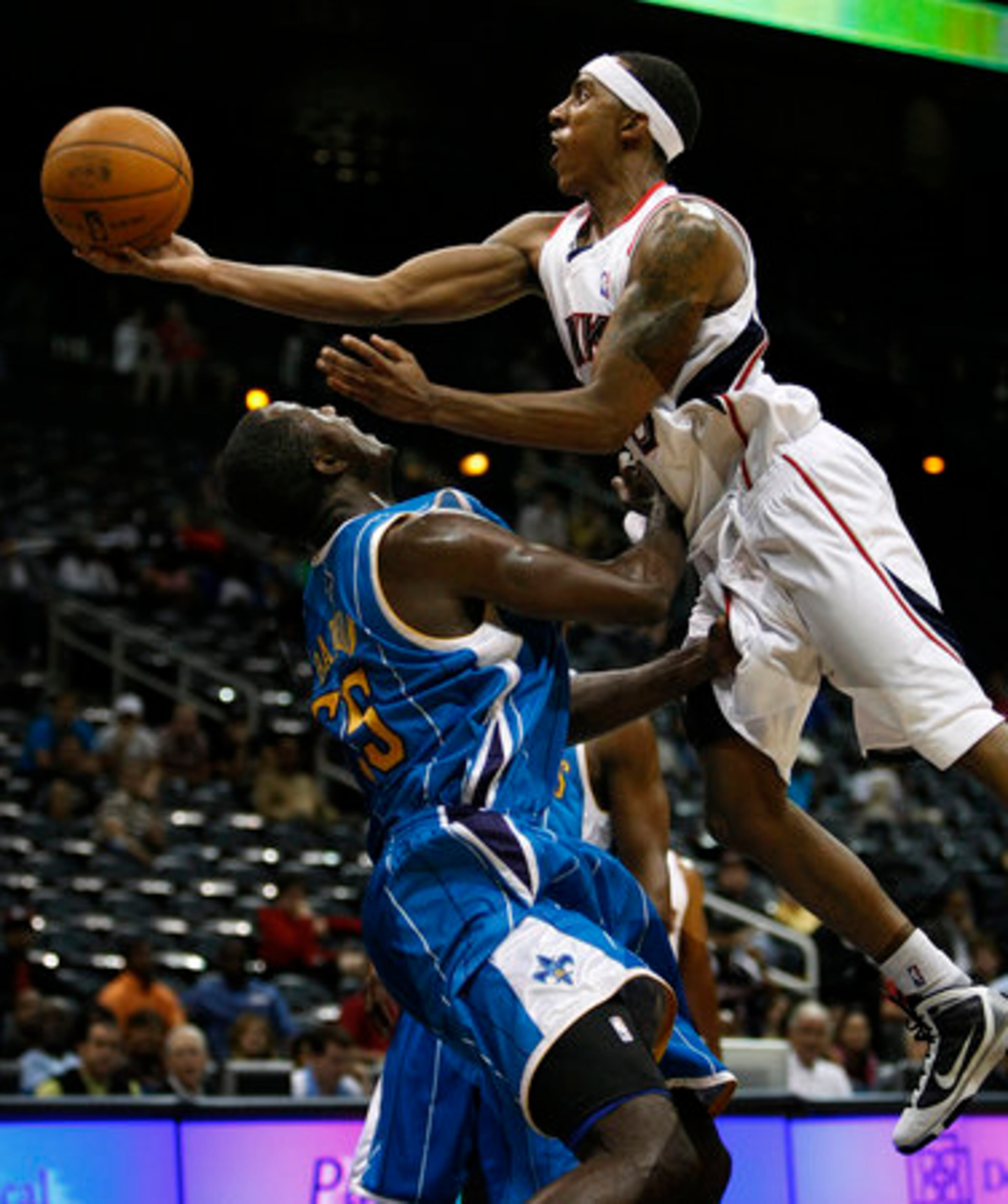 Hawks guard Jeff Teague (right) collides with New Orleans Hornets # 55 Earl Barron as he drives to the basket.