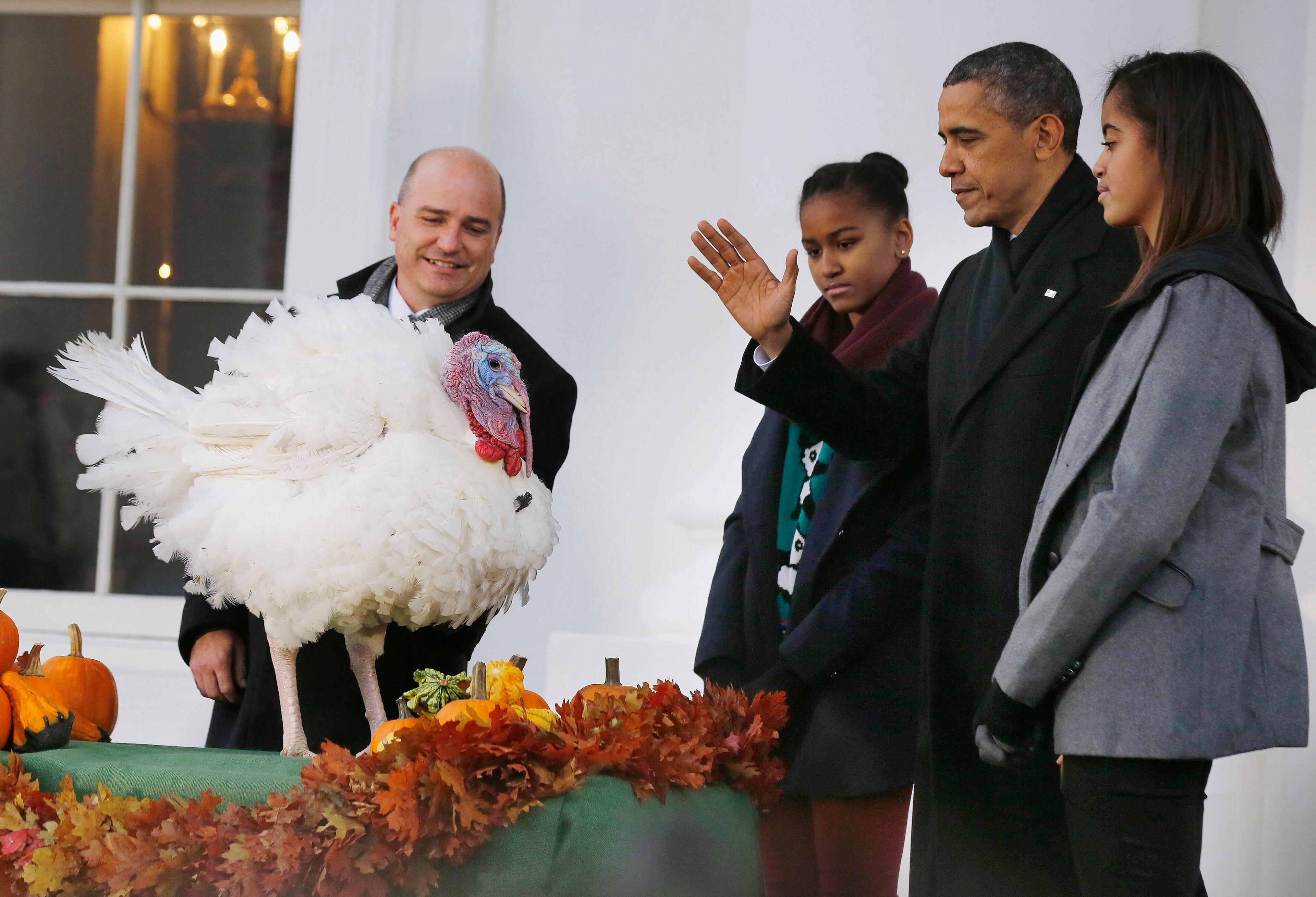 President Barack Obama joins his daughters Sasha (third right) and Malia (right) as they pardon National Thanksgiving Turkey Popcorn on the North Portico of the White House in Washington on Nov. 27, 2013. Chairman of the National Turkey Federation John Purkel looks on at left.