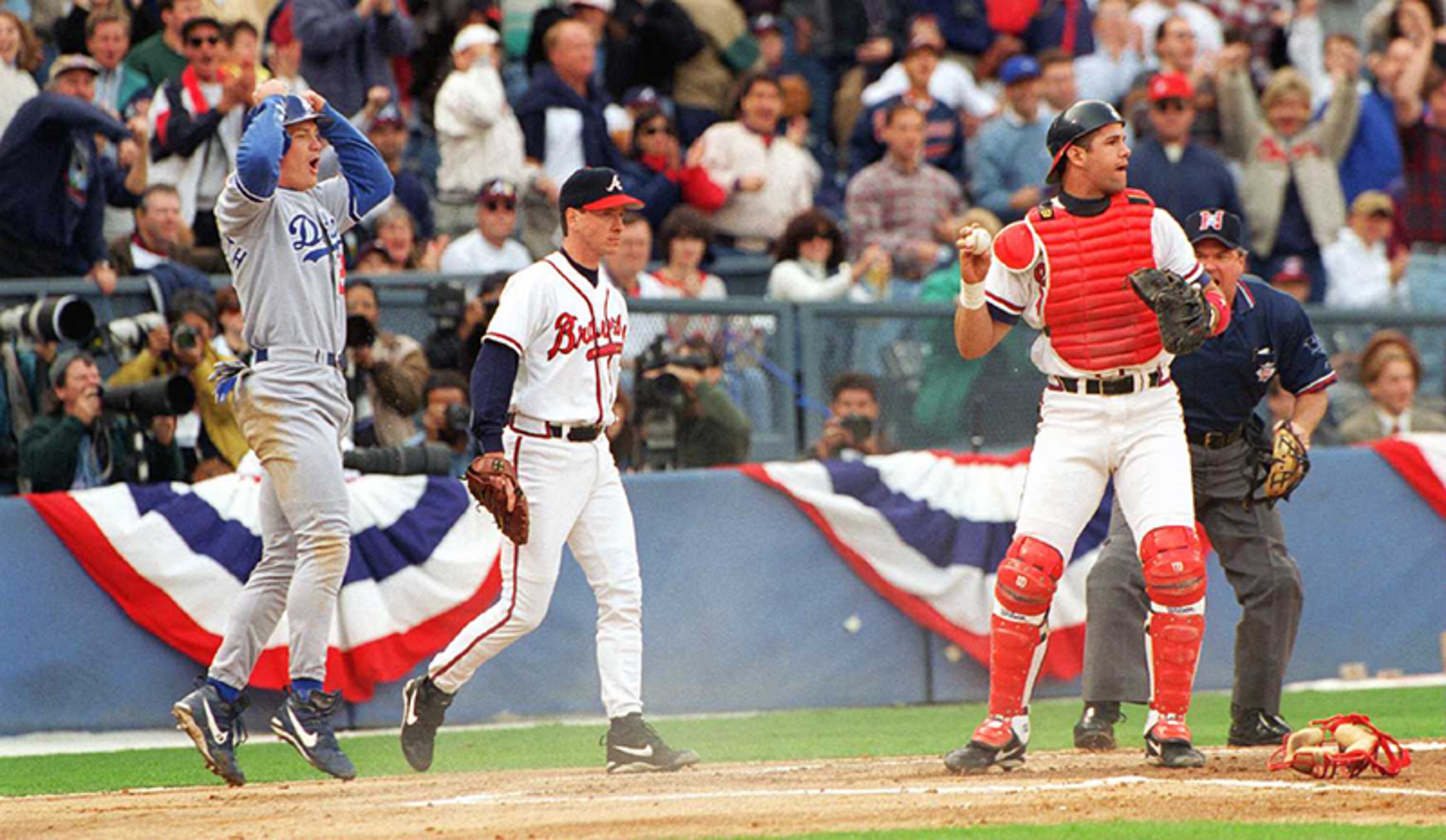 Dodgers outfielder Todd Hollandsworth (left) jumps up in disbelief after being called out at the plate after Atlanta Braves' catcher Javier Lopez's tag. Pitcher Tom Glavine backs up the play on in Game 3 of the NLDS at the Atlanta-Fulton County Stadium in Atlanta.