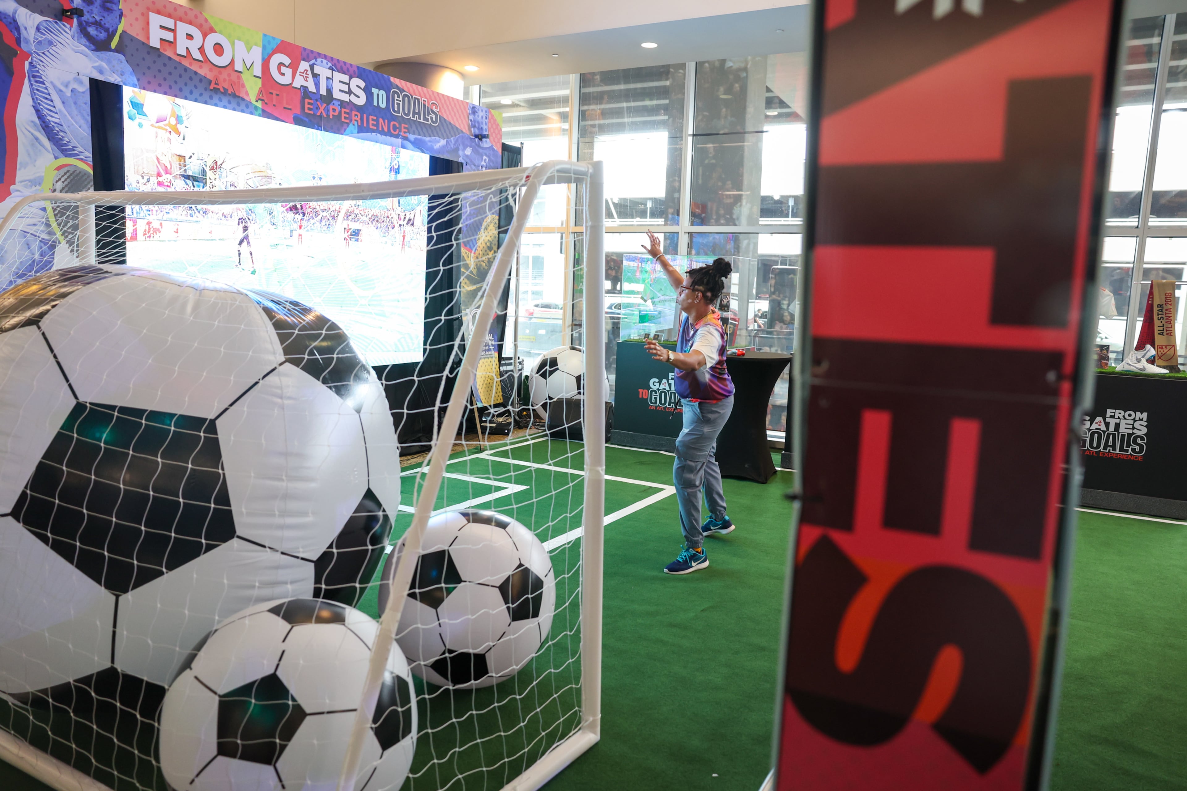 Jessica Payden, an employee with the production company Premiere Entertainment, plays an interactive video game at the "From Gates to Goals" exhibit celebrating the FIFA World Cup at Hartsfield-Jackson airport international terminal in Atlanta on May 27, 2026. (Arvin Temkar/AJC)