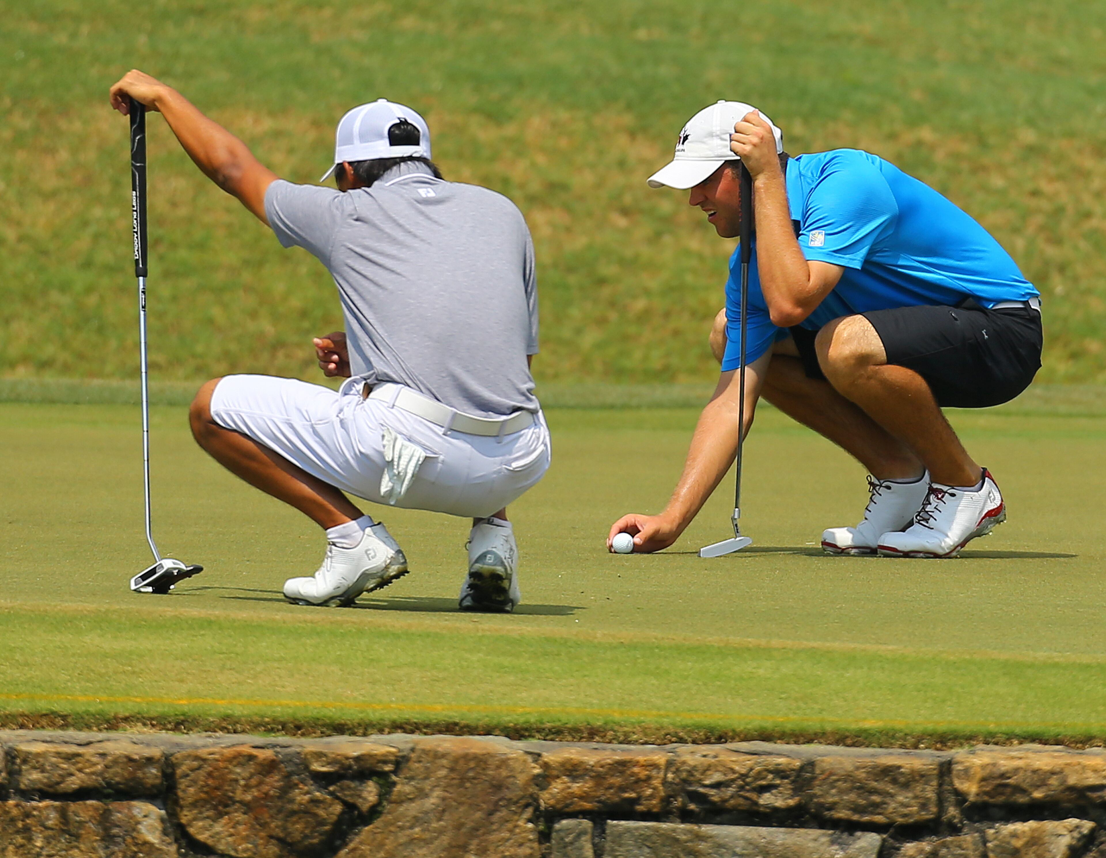 Gunn Yang, left, and Corey Conners, right, both look over their birdie putts on the fourth green during the afternoon round of the 36-hole championship match of the 2014 U.S. Amateur Championship at Atlanta Athletic Club on Sunday, August 17, 2014, in Johns Creek. Both made par on the hole.