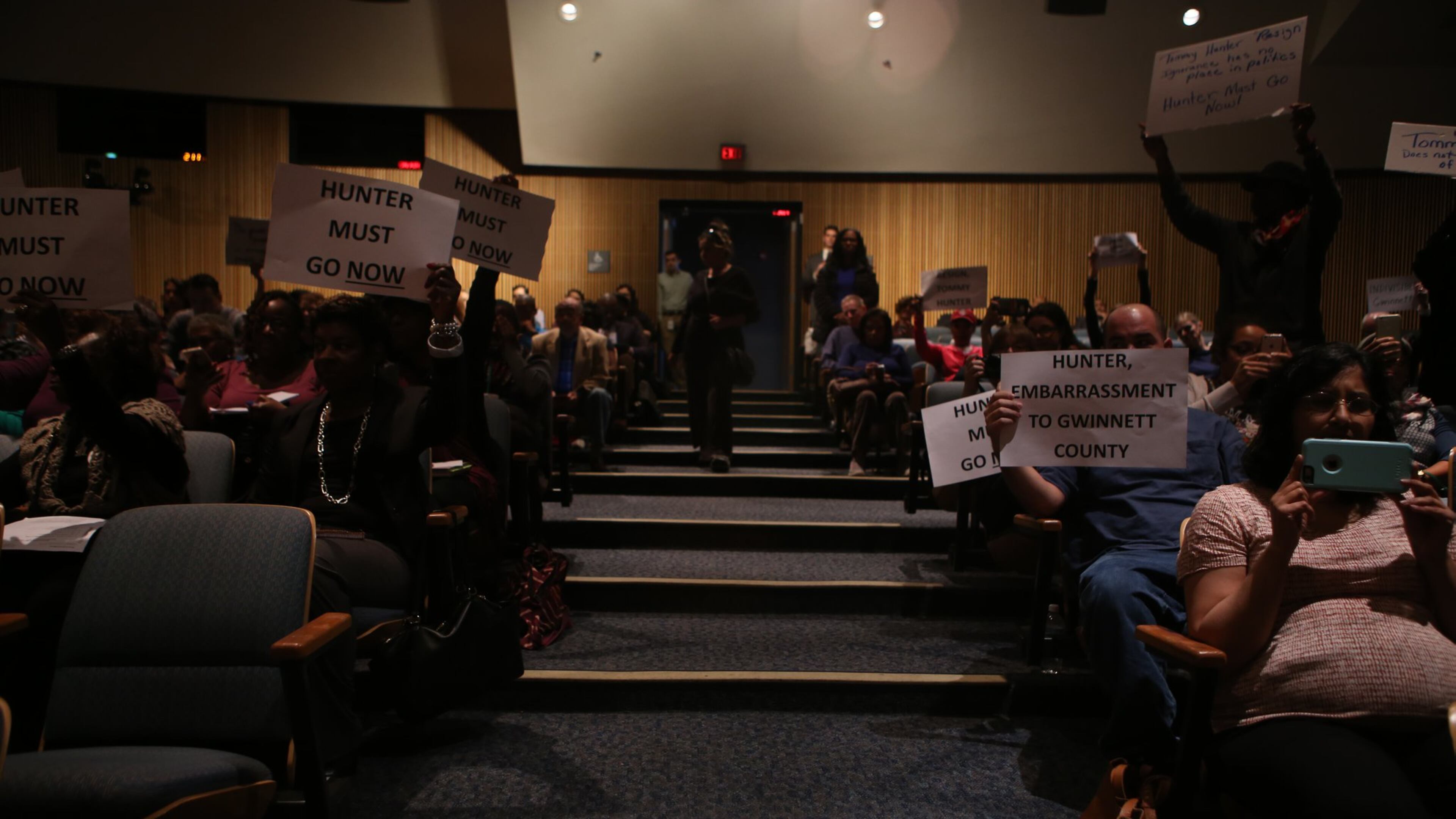 Protesters brought signs to voice their opinions on Tommy Hunter and his comments towards John Lewis to the Gwinnett County Board of Commissioners meeting Tuesday. (HENRY TAYLOR / HENRY.TAYLOR@AJC.COM)