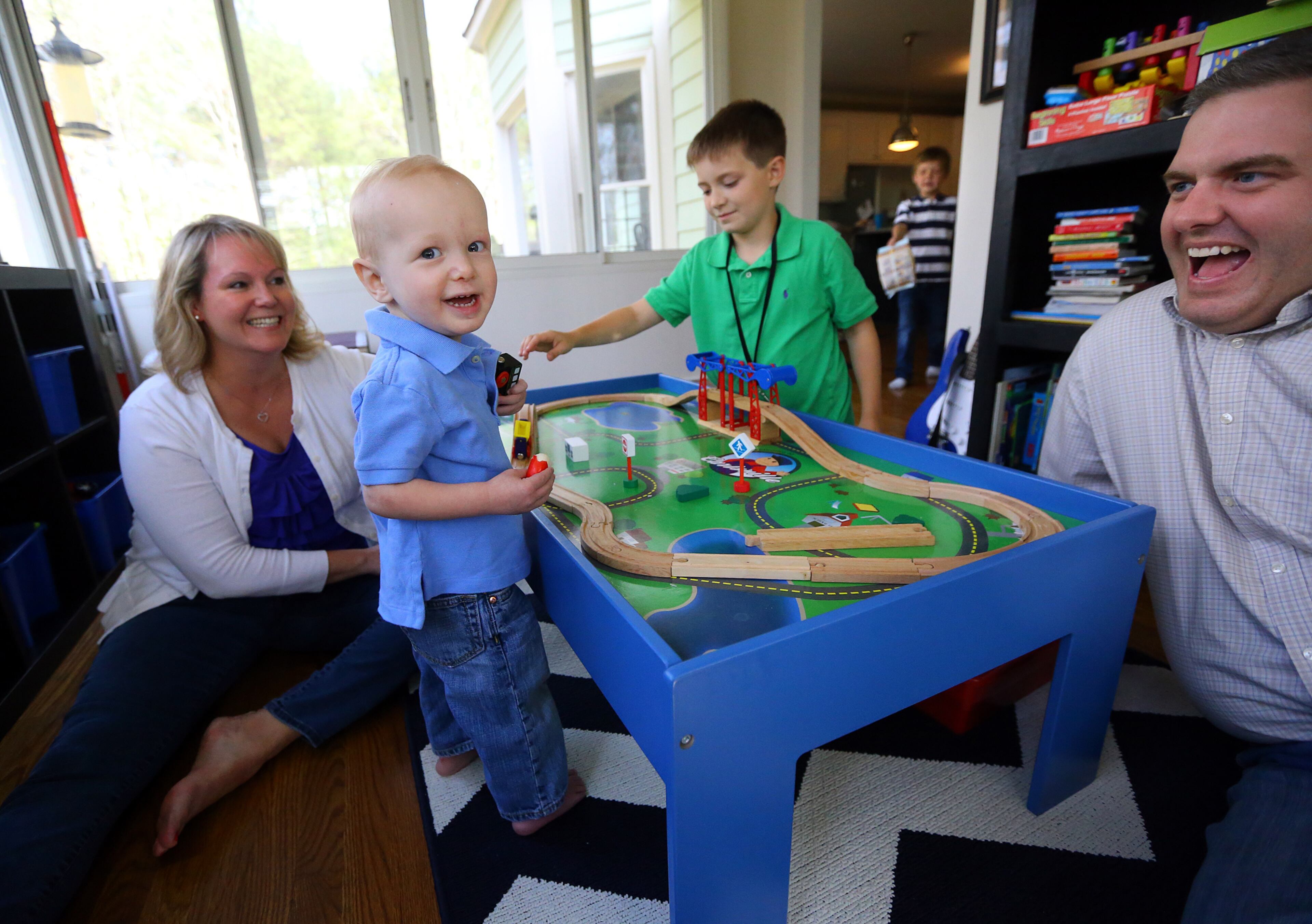 Ashley Shepardson (from left), her 22-month-old son Zach, who has congenital heart disease, Teddy, 8, Charlie, 6, and John Shepardson enjoy family time with a train set in the play room of their home on Thursday, April 17, 2014, in Milton. CURTIS COMPTON / CCOMPTON@AJC.COM