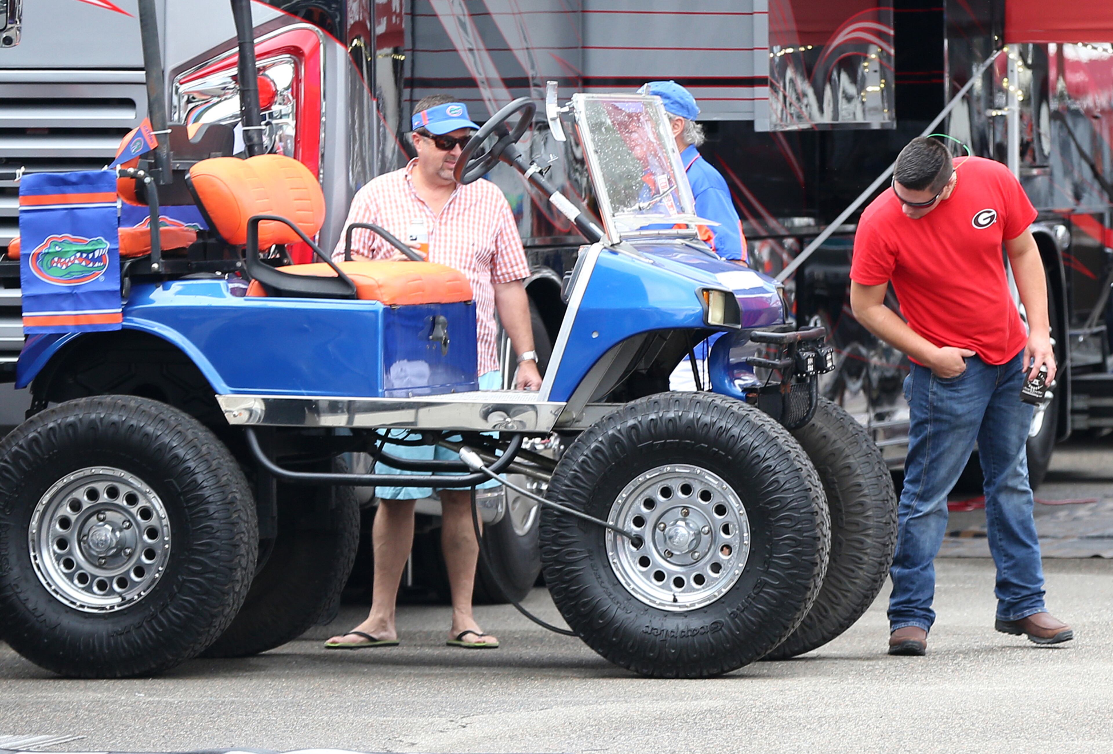 A Georgia fan checks out the oversized tires on the golf cart of a Florida fan while hanging out in the RV Park Friday. (Curtis Compton/ccompton@ajc.com)