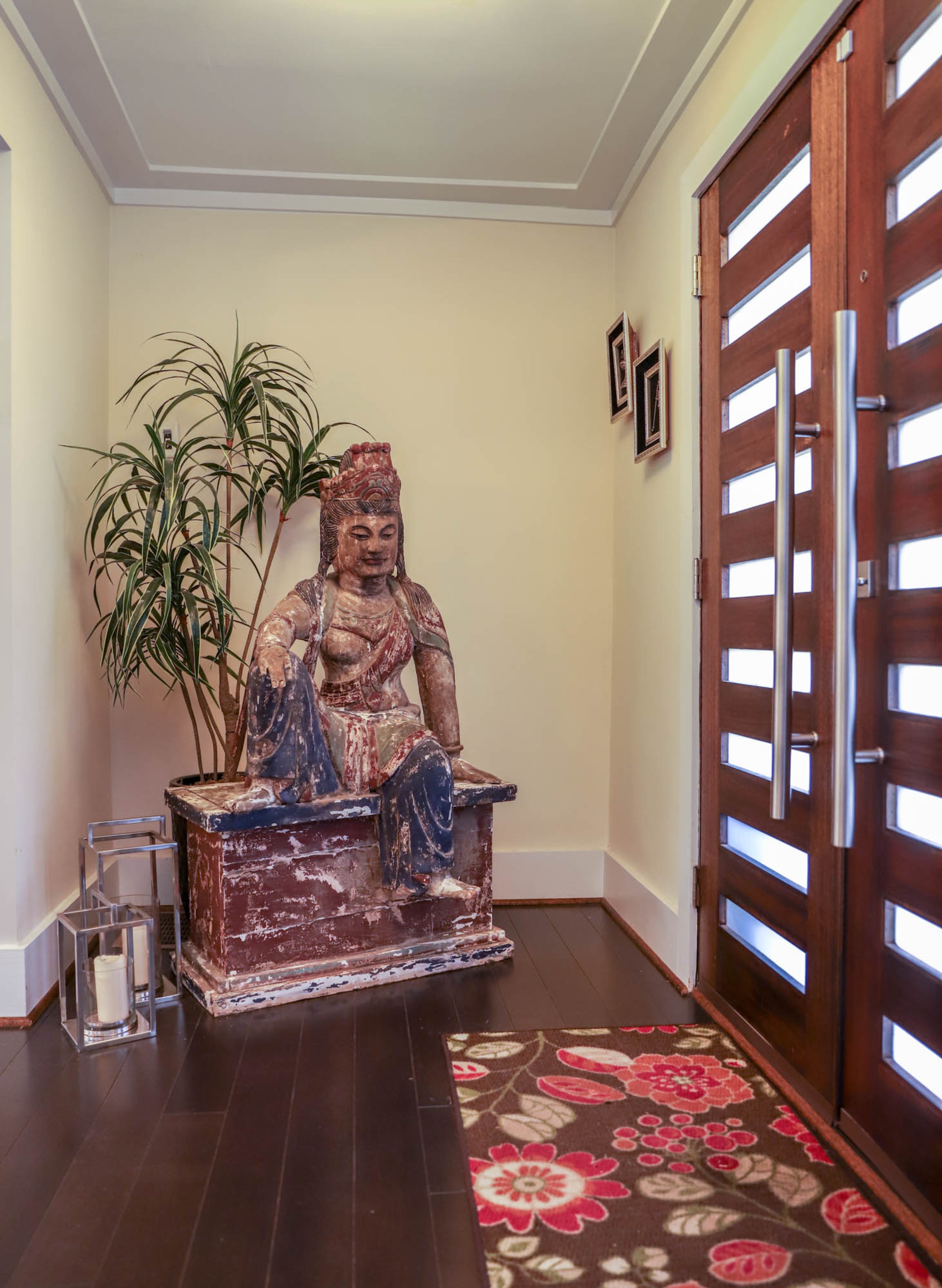 The entryway features a new, contemporary door from Builders Surplus and a Buddha statue from Scott Antique Market that welcomes visitors to the Rosenhafts' home.