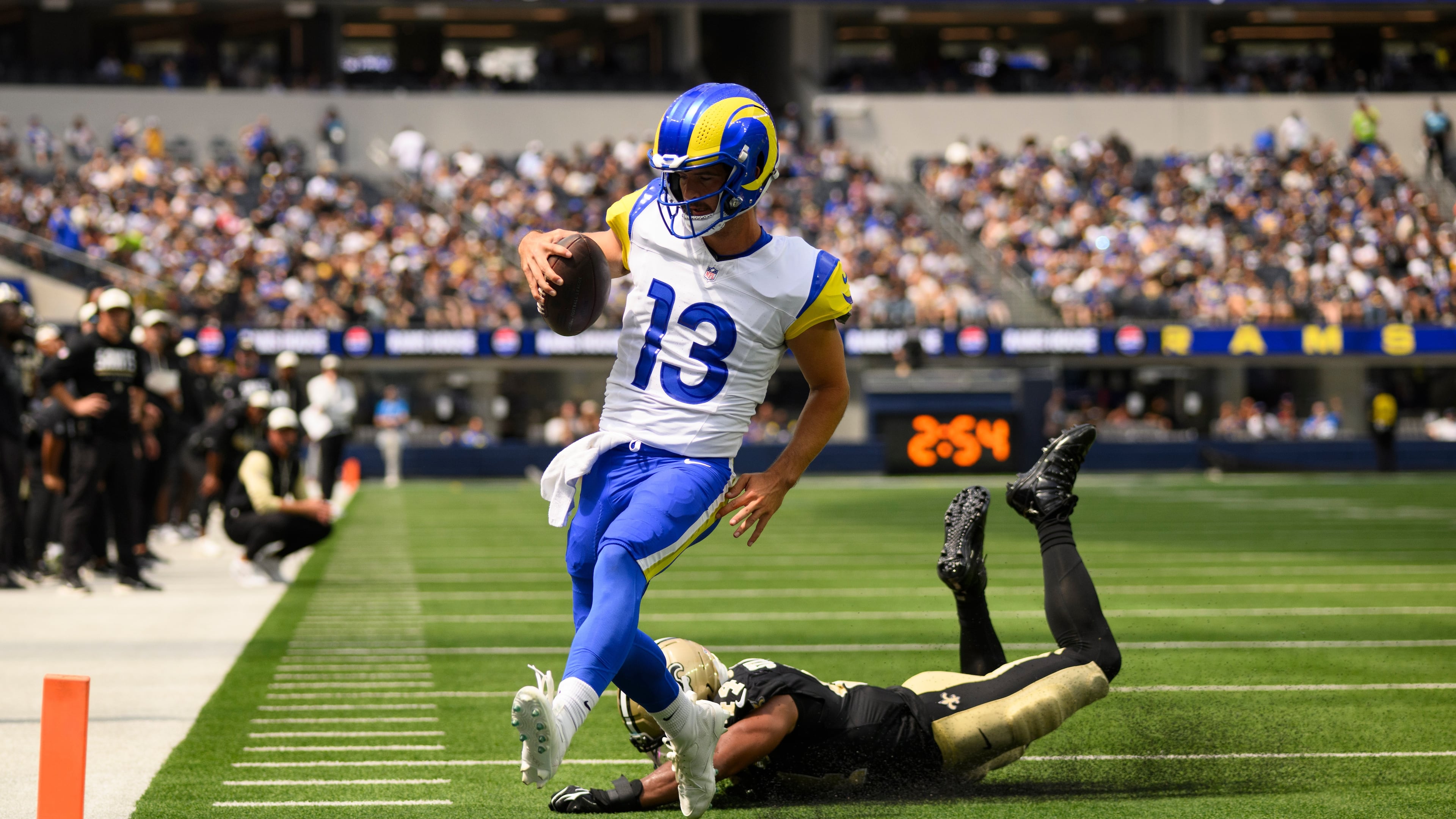 Rams quarterback Stetson Bennett IV (left) runs past Saints linebacker Isaiah Stalbird for a touchdown Saturday, Aug. 22, 2026, in Inglewood, Calif. Bennett was 19-for-31 for 181 yards passing and two rushing TDs. (Kyusung Gong/AP)