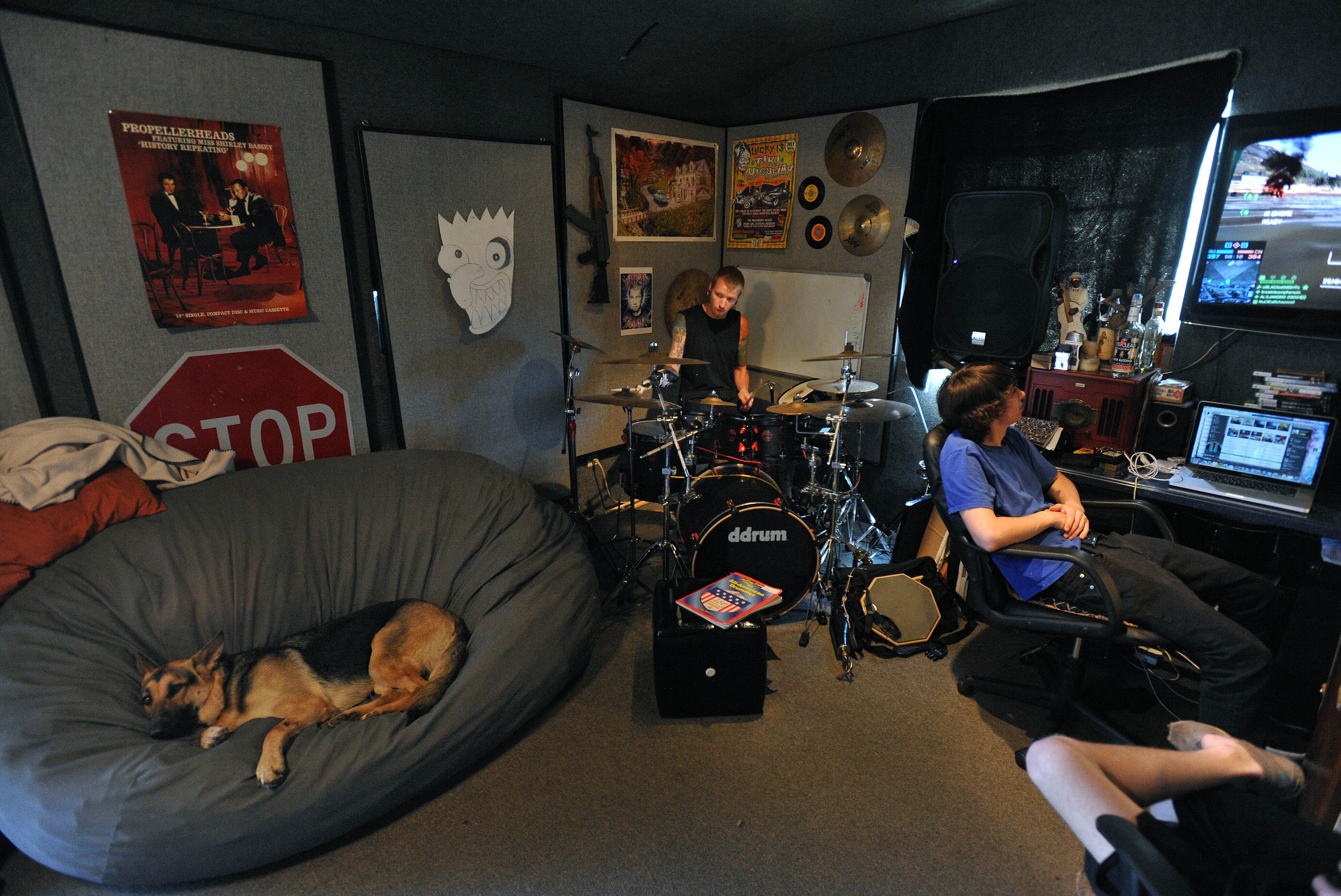 Jason Barnes, a drummer who lost his right hand in an accident, relaxes in his music room with his dog Stella, and his friend Jake Pippin, on Tuesday April 1, 2014 in Locust Grove, Ga. David Tulis / AJC Special
