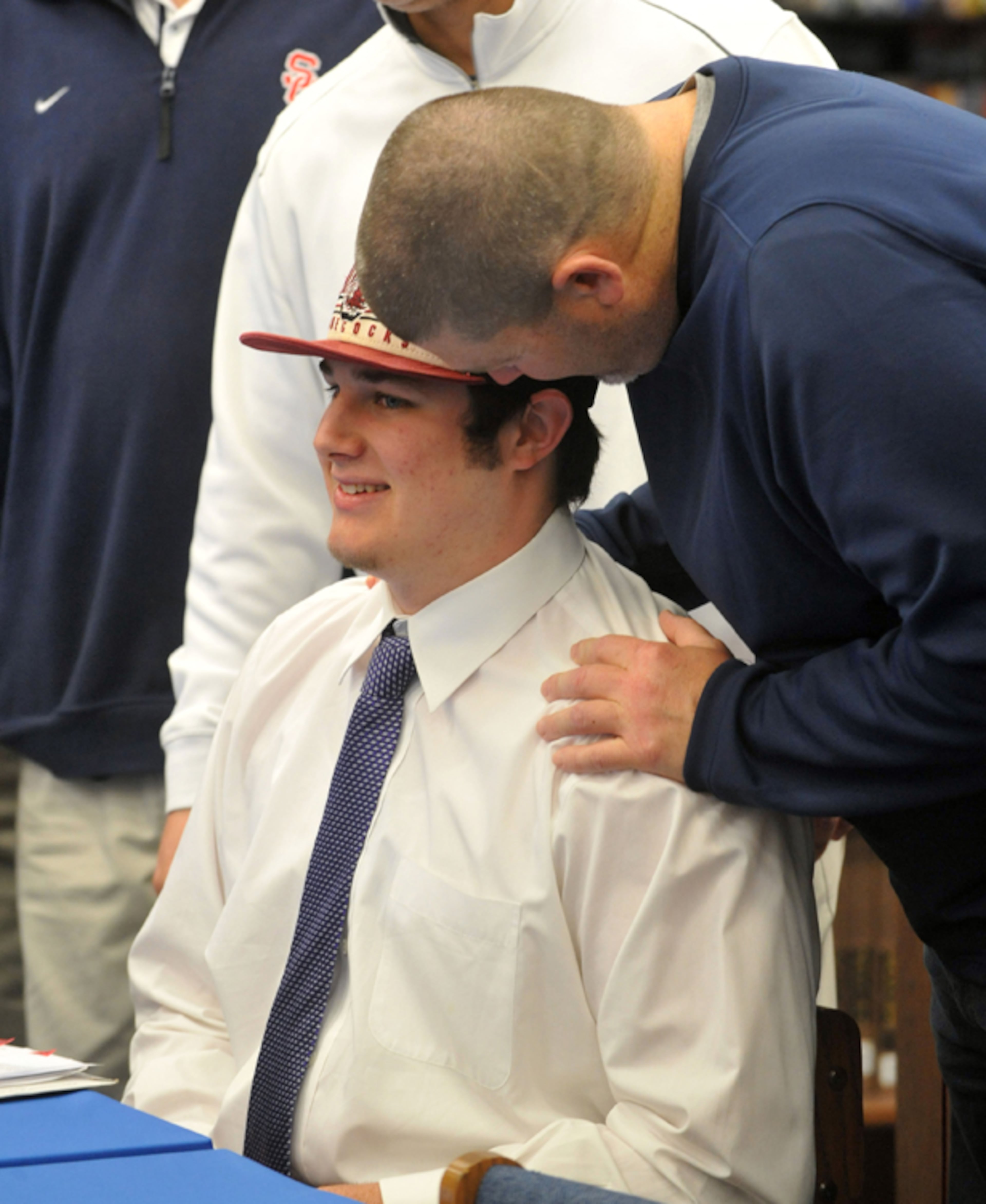 Alan Knott gets words of encouragement from his offensive line coach, Jamie Glover, after he signed with South Carolina on National Signing Day at Sandy Creek High School in Tyrone.