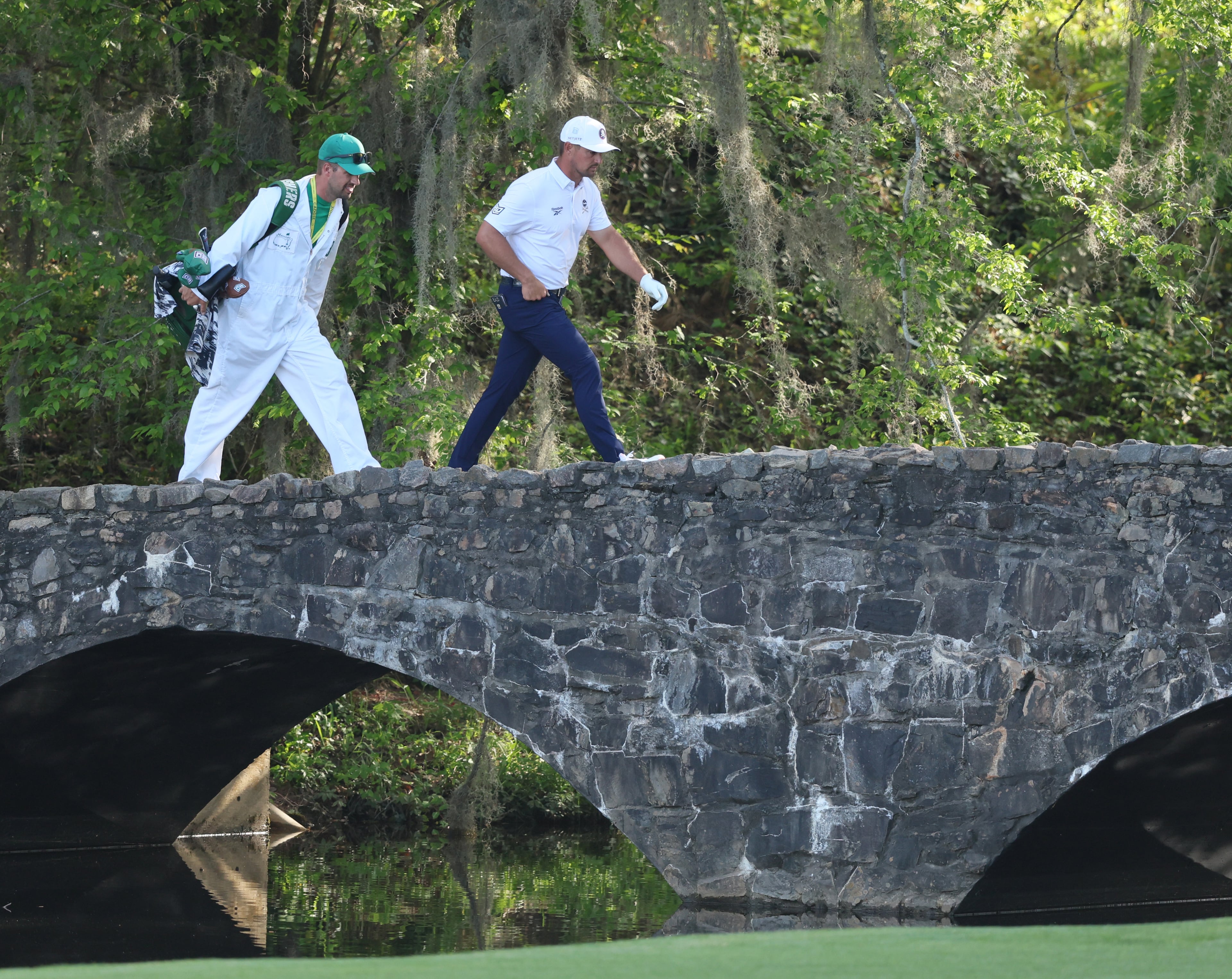 Bryson DeChambeau and caddie Greg Bodine cross bridge on 13th hole during third round of the Masters golf tournament, at Augusta National Golf Club, Saturday, April 12, 2025, in Augusta, Ga. (Jason Getz / AJC)