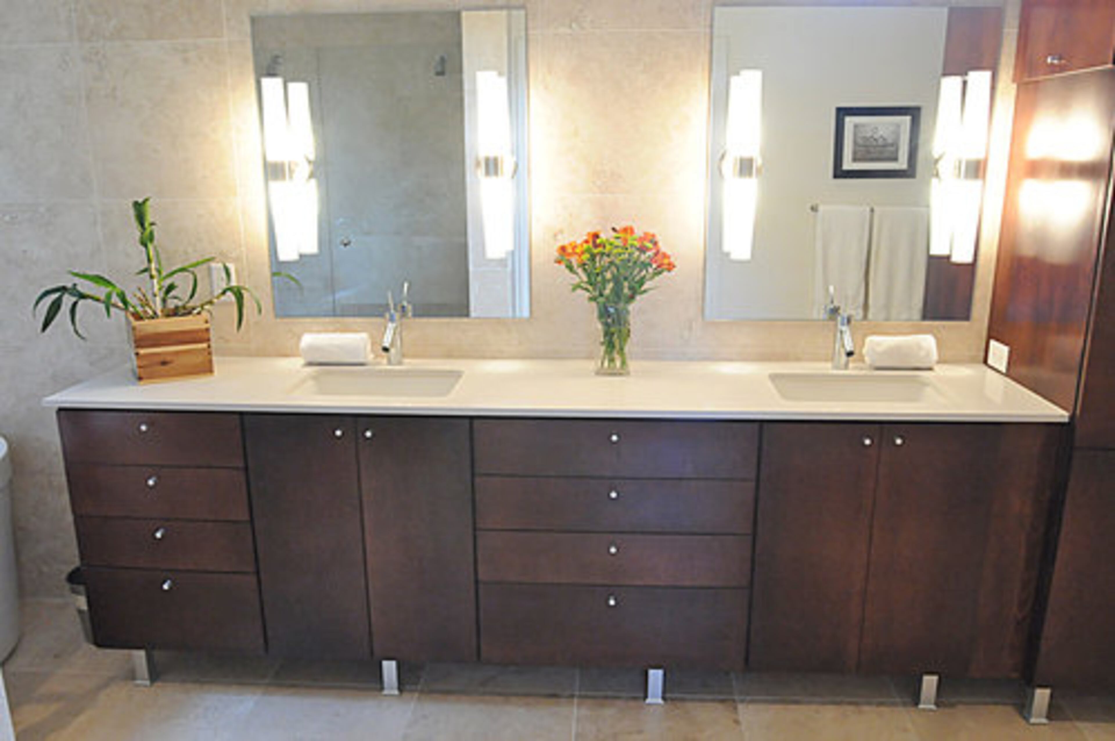 The bathroom continues the minimalist, efficient design that can be found throughout the home. The bathroom features dual sinks, a glassed-in shower, sconce-like light fixtures adorning the mirrors and plenty of storage to keep the area clutter-free. Again, fresh flowers add a nice touch of color.