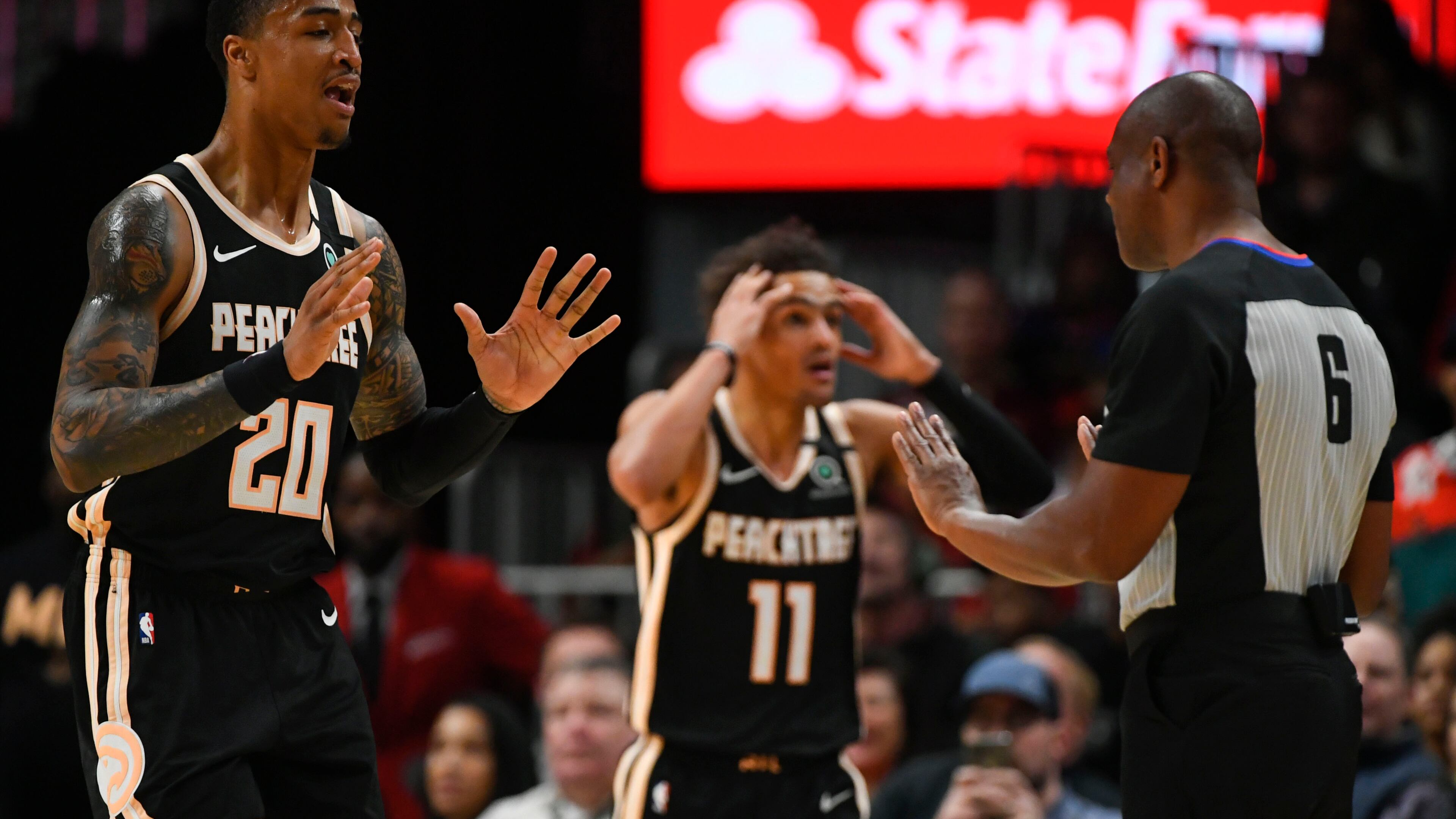 Hawks forward John Collins (20) and guard Trae Young (11) react to a technical foul called against Young by a referee during the first half against the Toronto Raptors, Monday, Jan. 20, 2020, at State Farm Arena in Atlanta.