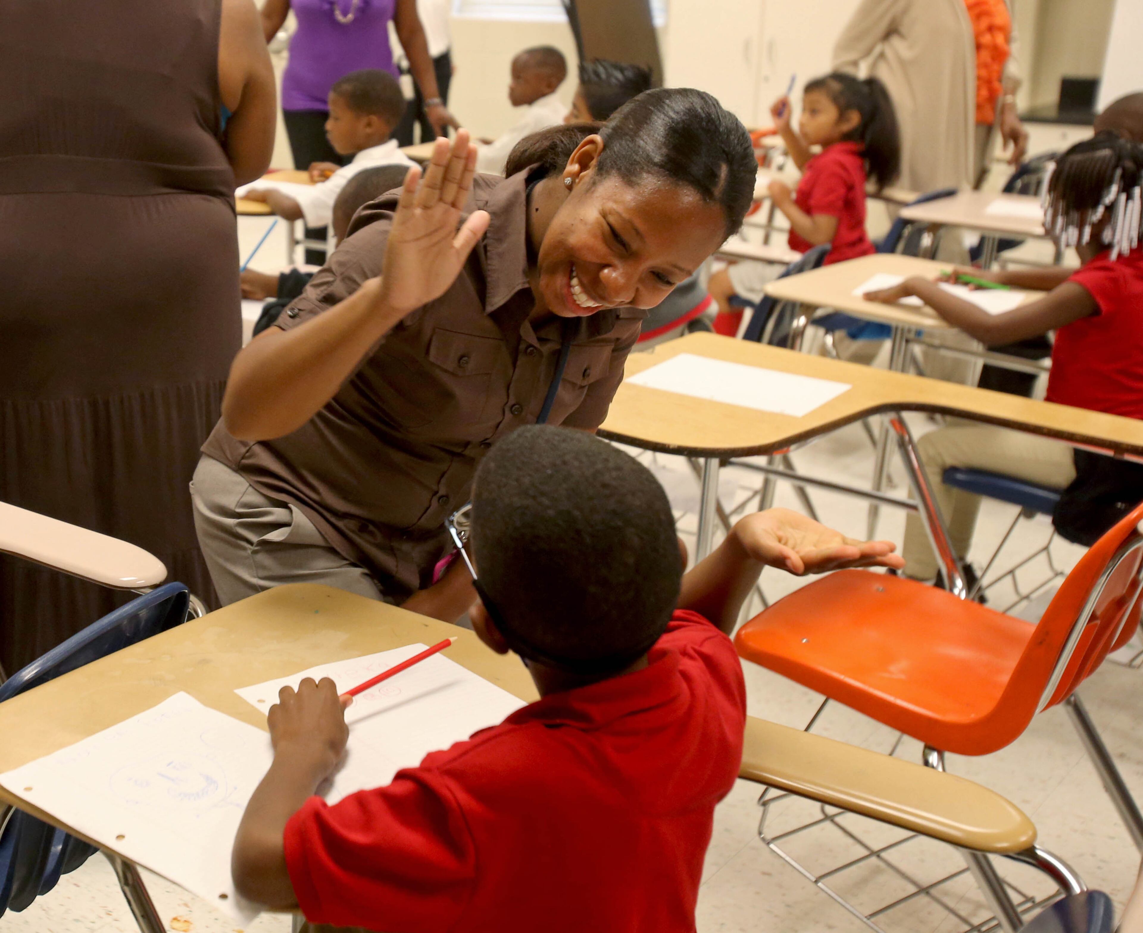 McNair Learning Academy first-grade teacher Danielle Pitts high-fives a student following a song during their first grade class at McNair High School on Wednesday morning in Atlanta.
