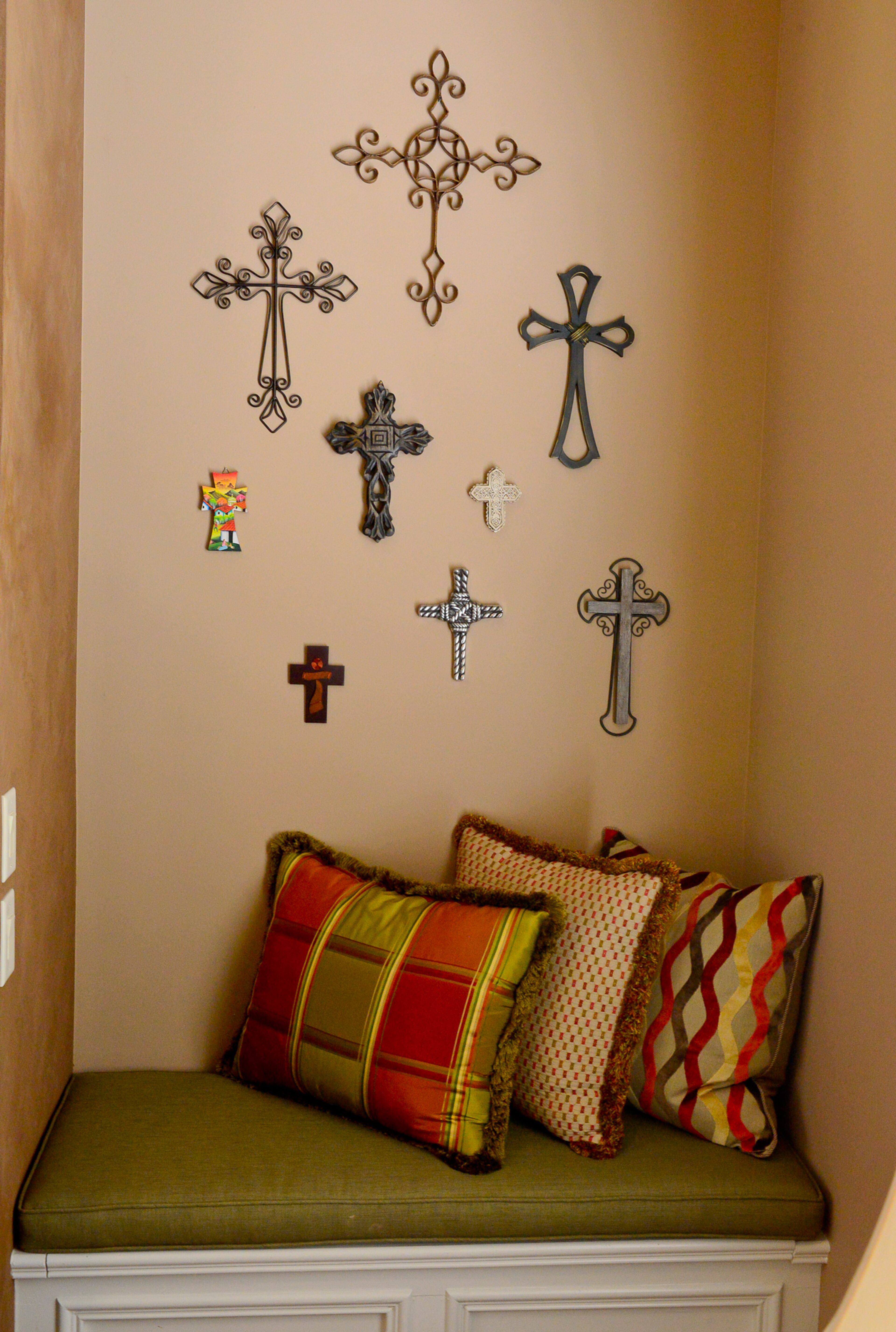 Many of the crosses filling a wall in the keeping room were acquired on mission trips in Latin America. Above the fireplace and flat screen TV, the wall is painted with Ralph Lauren suede paint.