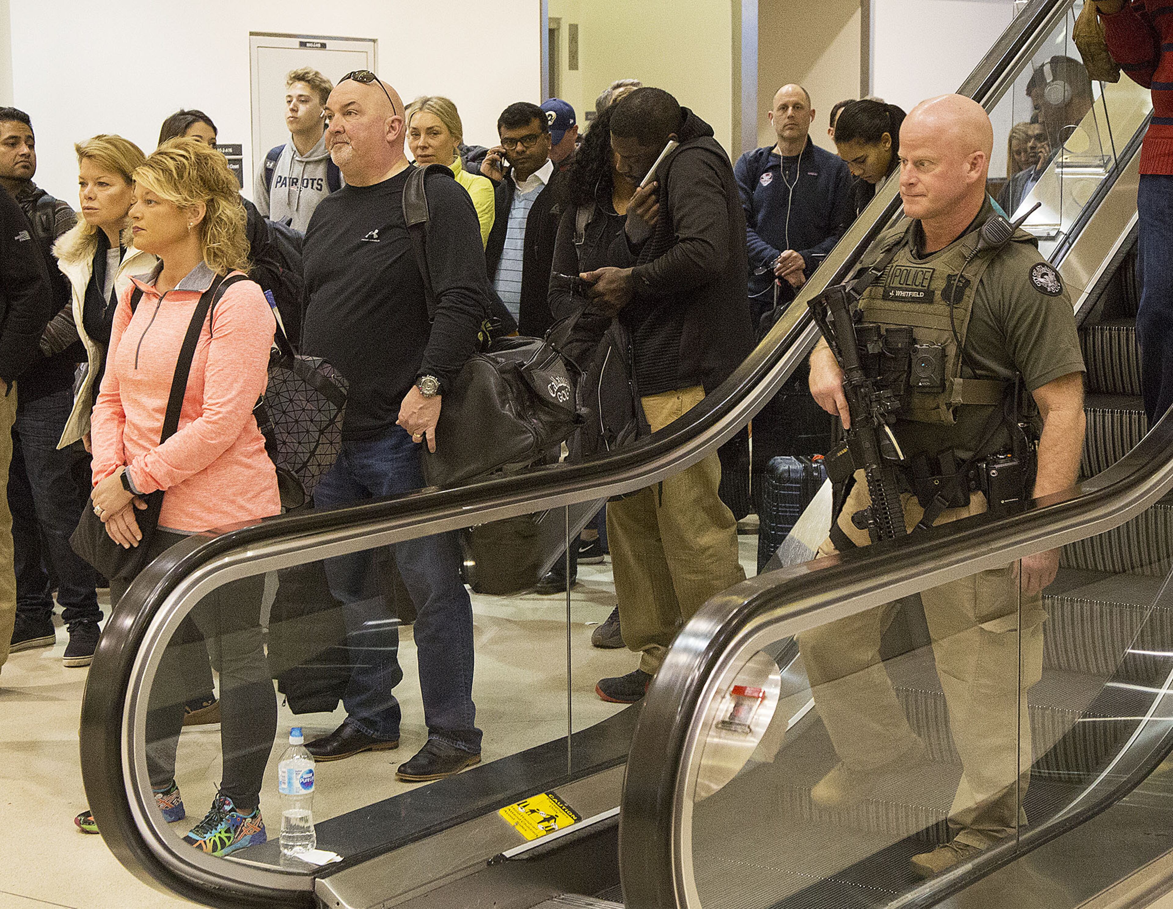 An armed policeman gets off an escalator near the security check as multiple security lines at Hartsfield-Jackson International Airport ran across the atrium then snaked through baggage claim in both domestic terminals on Monday February 4th, 2019. Official expected over 100,00 travelers to pass through the airport today. (Photo by Phil Skinner)