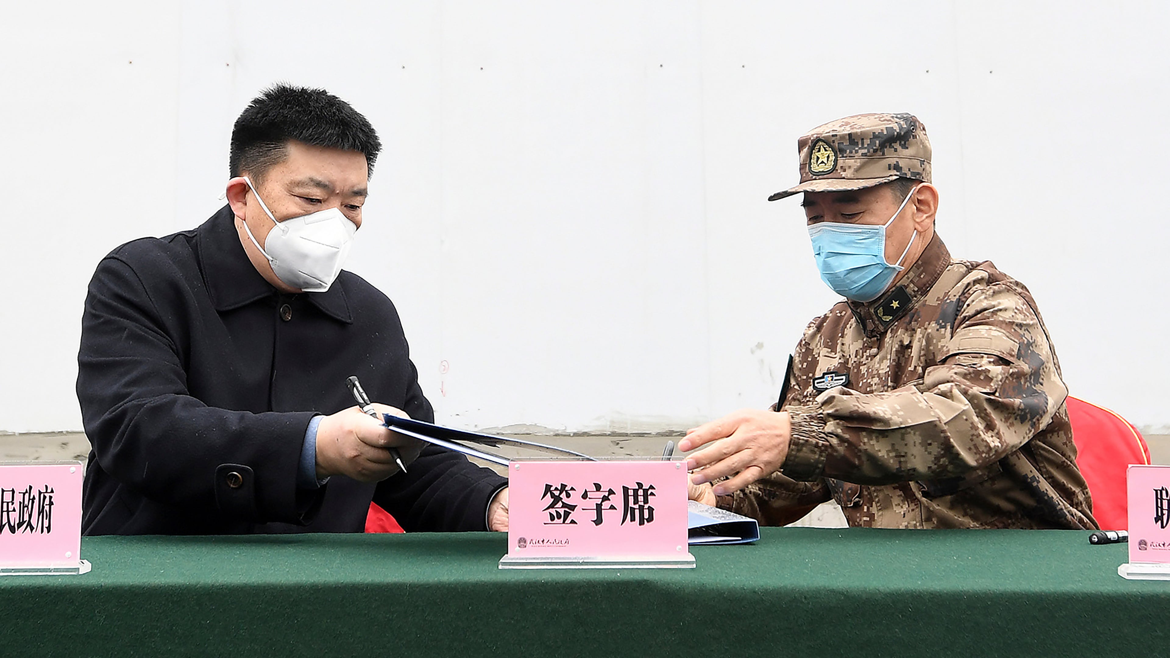 Zhou Xianwang, left, the mayor of Wuhan, exchanges documents with Bai Zhongbin, right, deputy commander-in-chief of China's People's Liberation Army (PLA) Joint Logistic Support Force, during a handover ceremony at the Huoshenshan temporary field hospital in Wuhan in central China's Hubei Province, Feb. 2, 2020. (Chinatopix via AP)