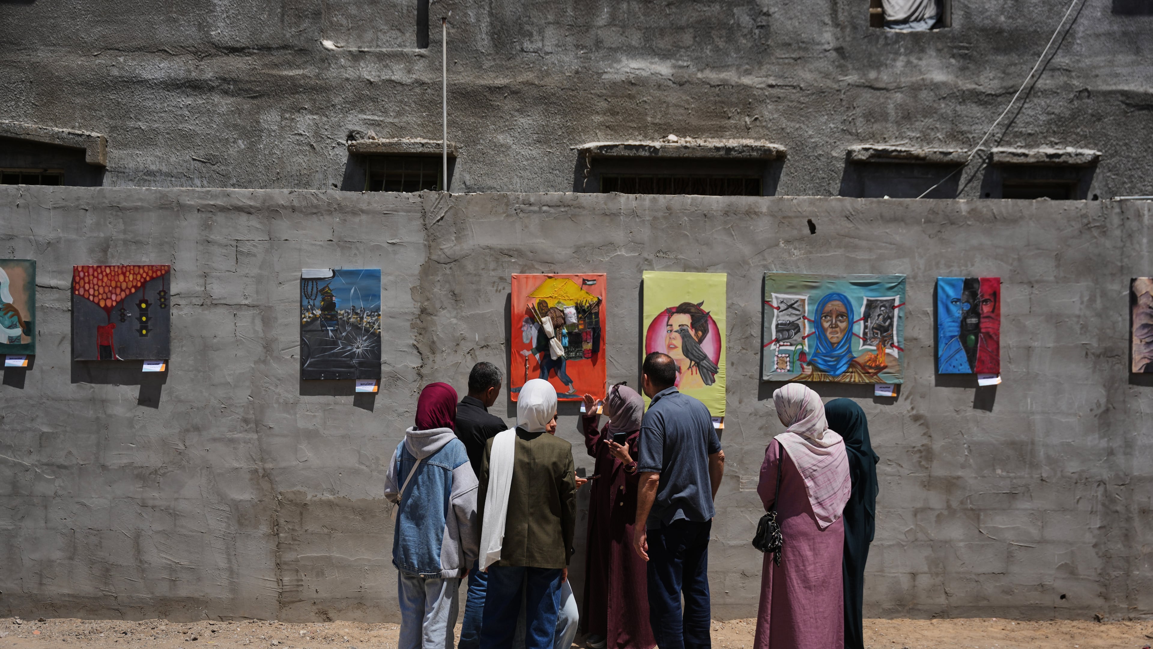 People look at paintings by Palestinian artists during an exhibition in Al-Bureij camp in the central Gaza Strip Tuesday, April 28, 2026. (AP Photo/Abdel Kareem Hana)