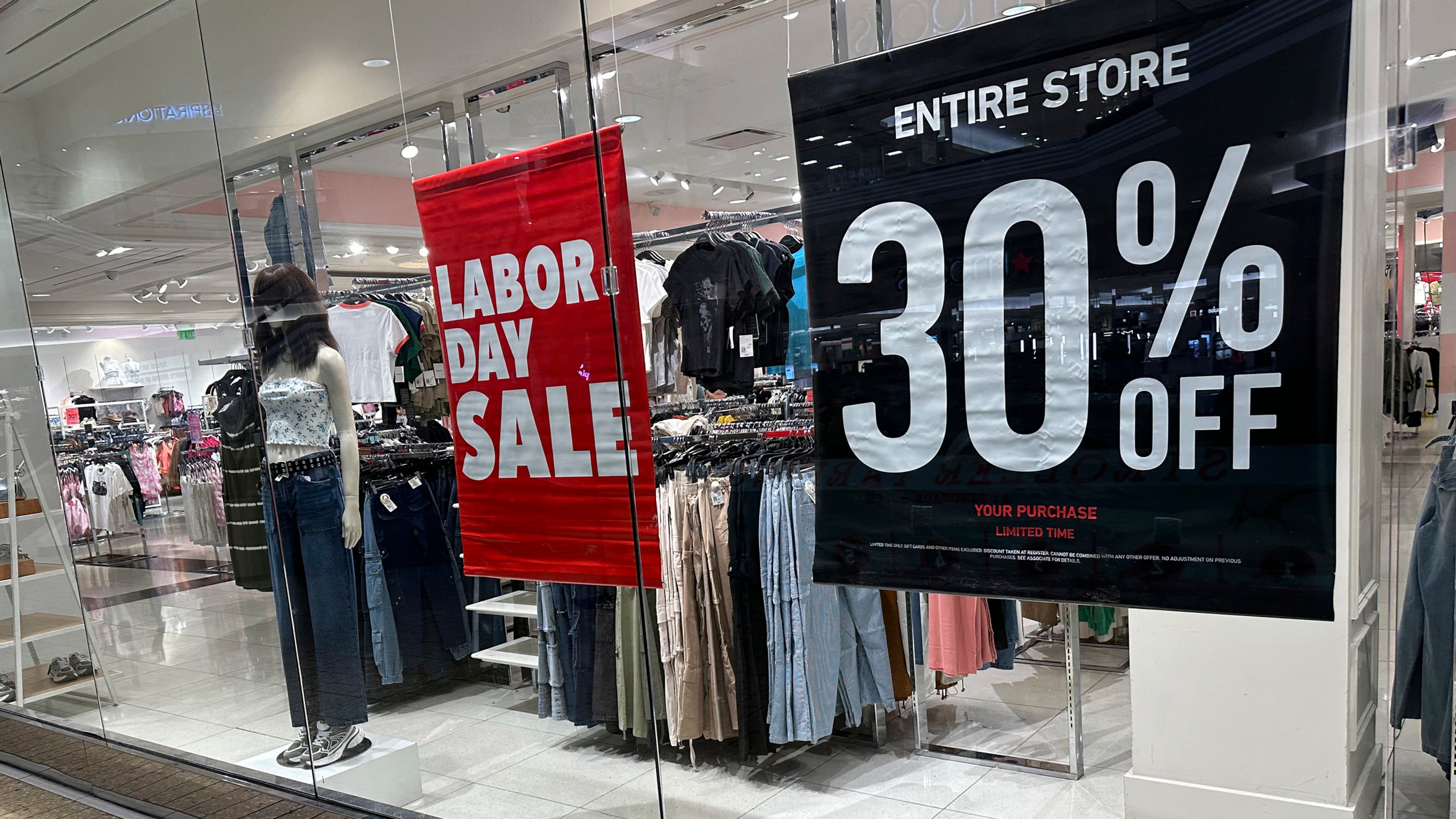 FILE - Signs announce a Labor Day sale in the window of a clothing store at a mall in Denver on Aug. 21, 2024. (AP Photo/David Zalubowski, File)