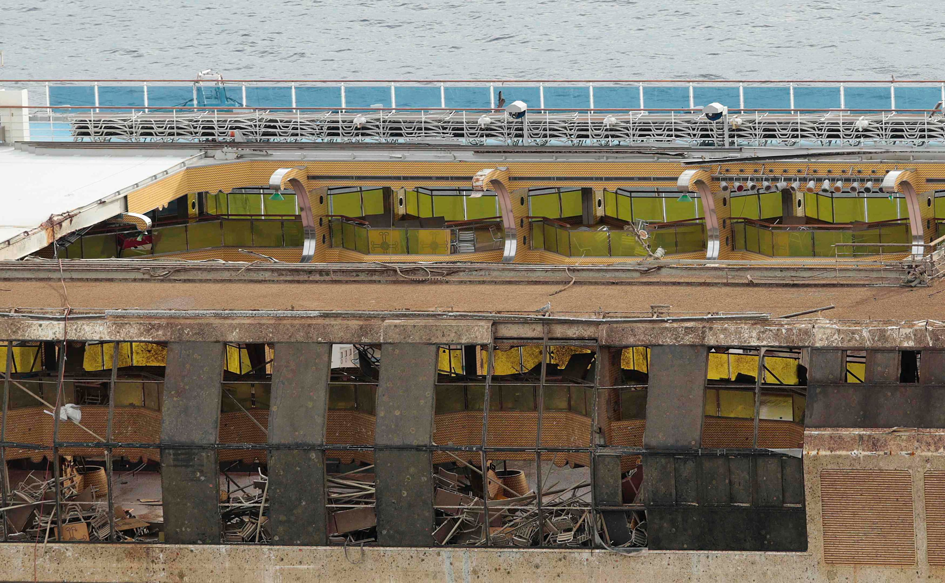 The damaged side of the capsized cruise liner Costa Concordia is seen at the end of the "parbuckling" operation outside Giglio harbour September 17, 2013. Salvage crews on the Italian island of Giglio raised the Costa Concordia cruise liner early on Tuesday, completing one of the most difficult and expensive wreck recovery projects ever performed. In a 19-hour operation which ended at 4.00 a.m. (0200 GMT), the 114,500 ship was pulled upright by a series of huge jacks and cables and left resting in 30 metres of water on underwater platforms drilled into the rocky sea bed. REUTERS/Tony Gentile