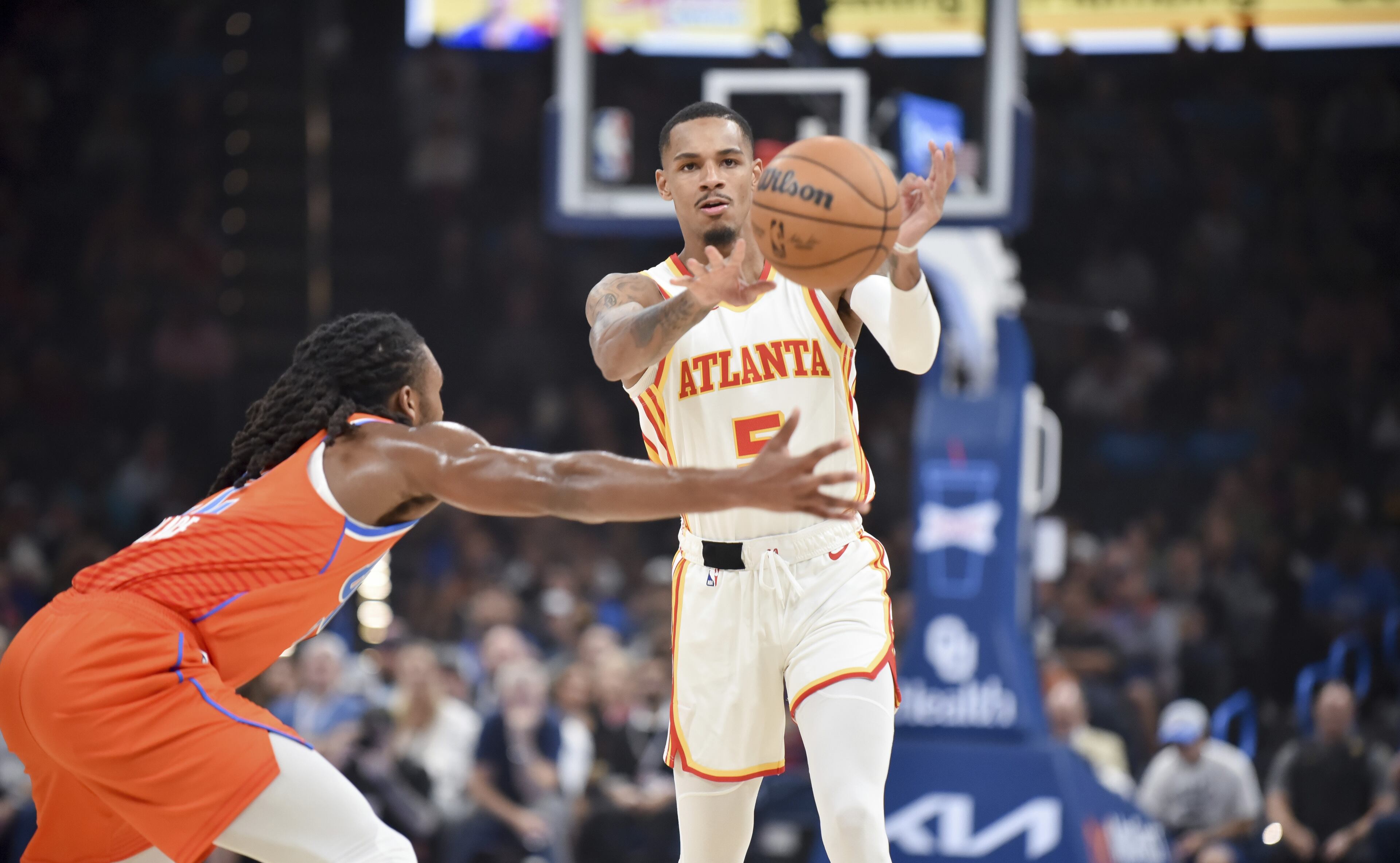 Hawks guard Dejounte Murray passes the ball around Oklahoma City Thunder guard Cason Wallace, left, in the first half of an NBA basketball game, Monday, Nov. 6, 2023, in Oklahoma City. (AP Photo/Kyle Phillips)