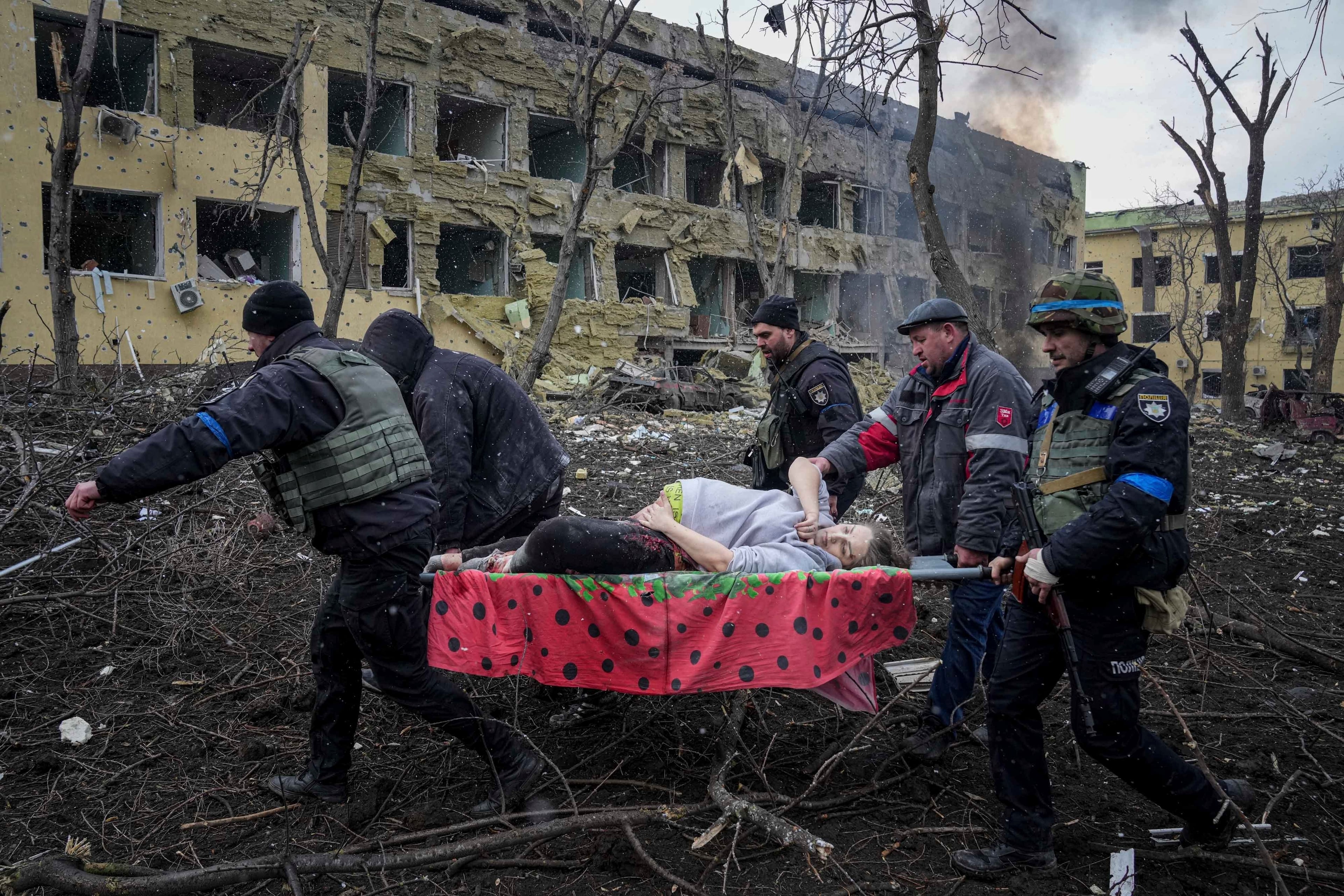 Ukrainian emergency employees and volunteers carry a wounded pregnant woman from a maternity hospital that was damaged by shelling on March 9 in the port city of Mariupol, Ukraine. The woman and her unborn child have since died after Russia bombed the facility where she was meant to give birth. (AP Photo/Evgeniy Maloletka, File)