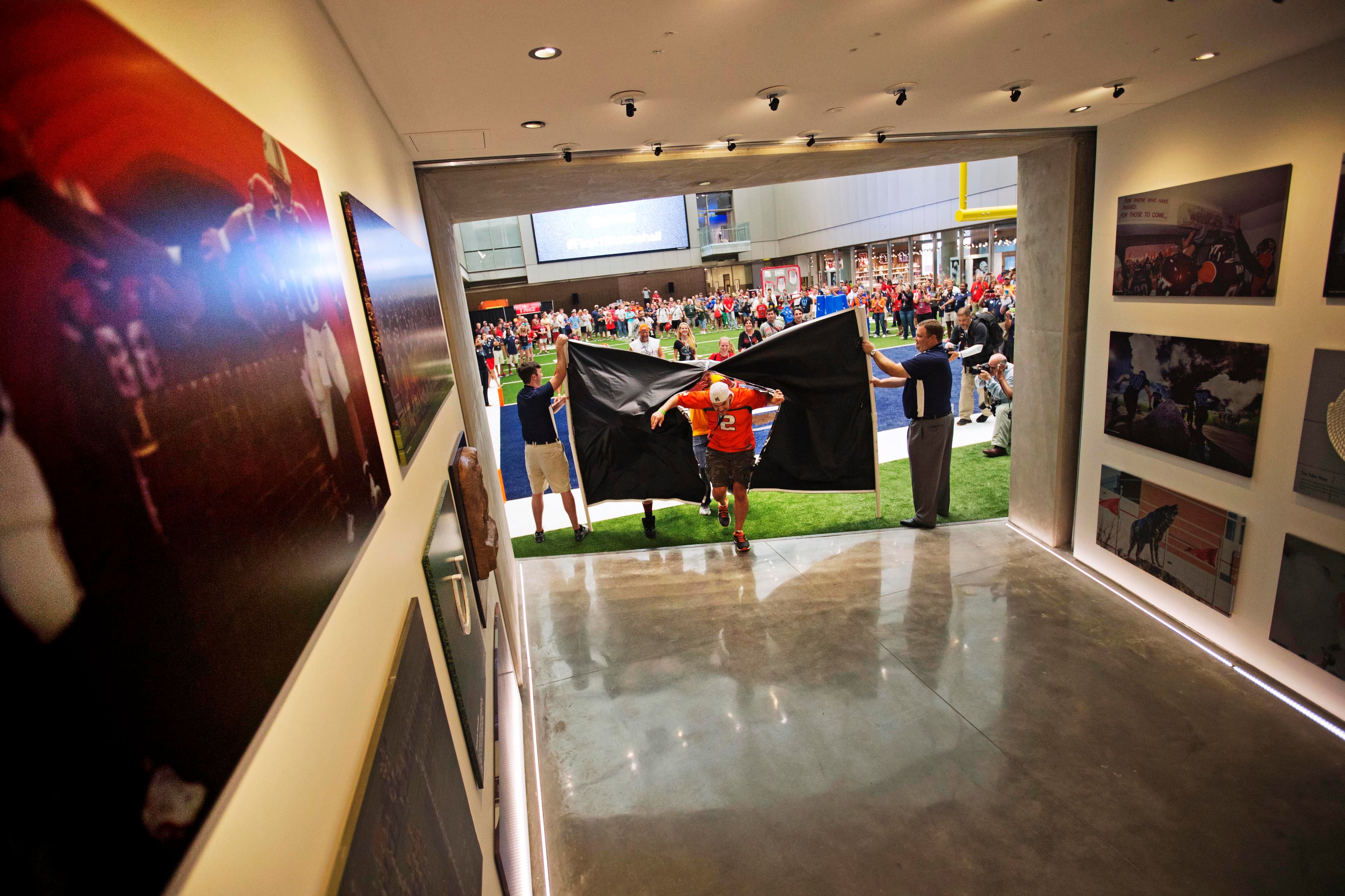 Fans run through a banner to be the first to tour the College Football Hall of Fame during a sleepover, Wednesday, Aug. 13, 2014, in Atlanta. The 94,000-square-foot facility features a 150 seat theater and a 45-yard replica football field. (AP Photo/David Goldman)