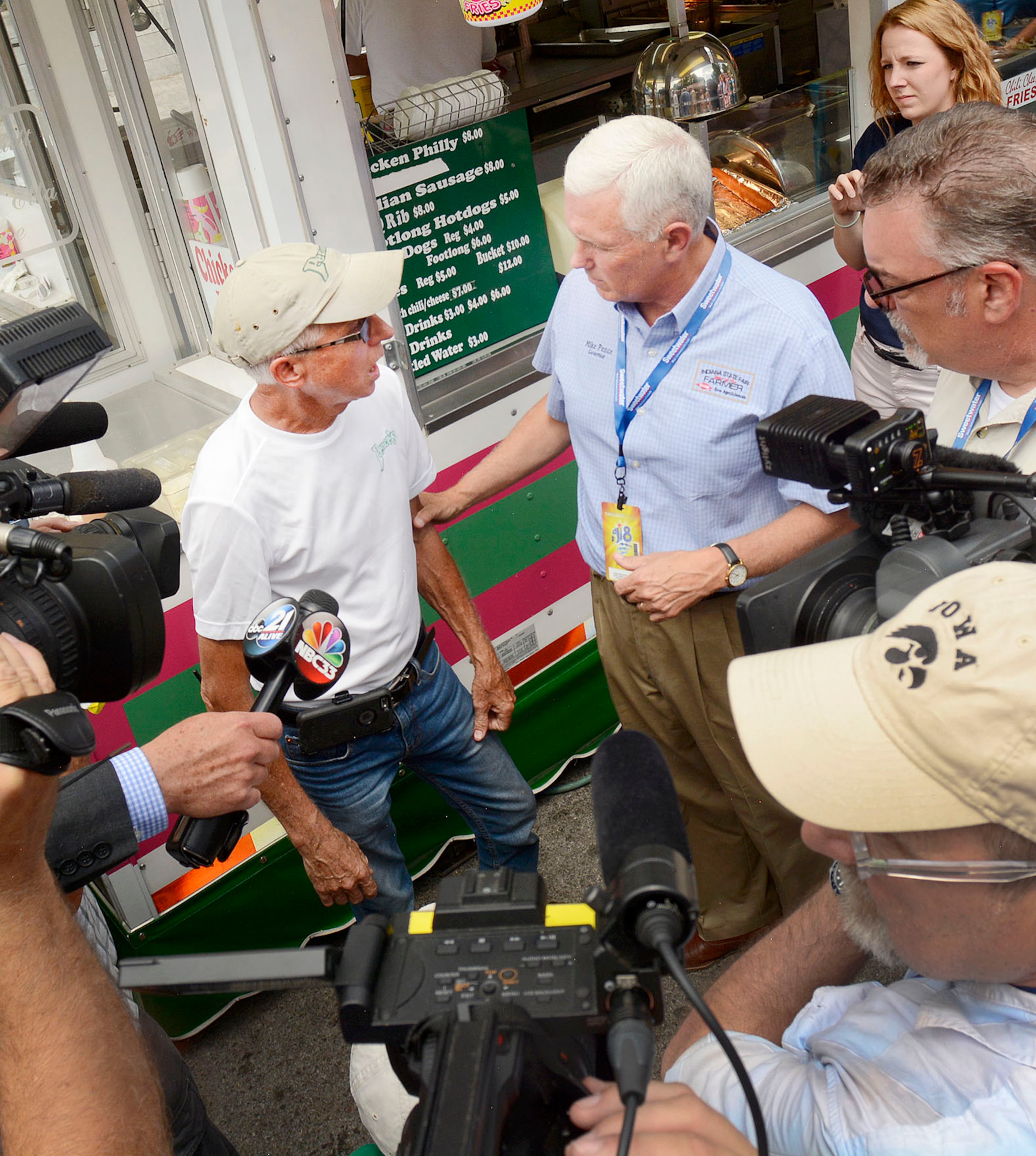 Mike Pence, purveyor of Philly cheese stakes from Bryan, OH, left, meets Mike Pence, governor of Indiana, in Junk Food Alley, part of the annual Three Rivers Festival in Ft. Wayne, Ind., Wednesday, July 13, 2016. The Gov. Pence posed for photos, watched a magic trick, drank a lemon shake-up and then answered questions about his meetings with Donald Trump. Pence repeated his earlier statement that nothing was offered by Trump and nothing was accepted by him. (Samuel Hoffman /The Journal-Gazette via AP)