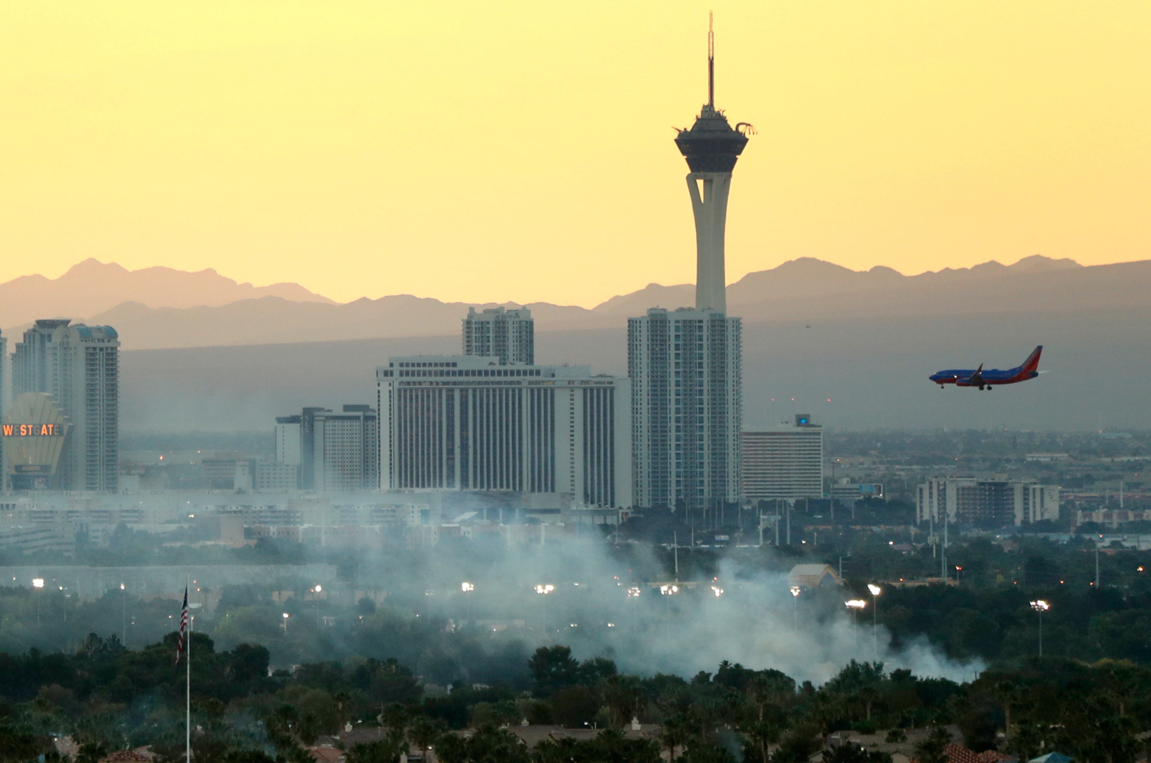 In this Tuesday, May 23, 2017 photo, a Southwest Airlines passenger jet makes an approach to McCarran International Airport as a one-acre brush fire burns on the south side of Sunset Park in Las Vegas. (Steve Marcus /Las Vegas Sun via AP)