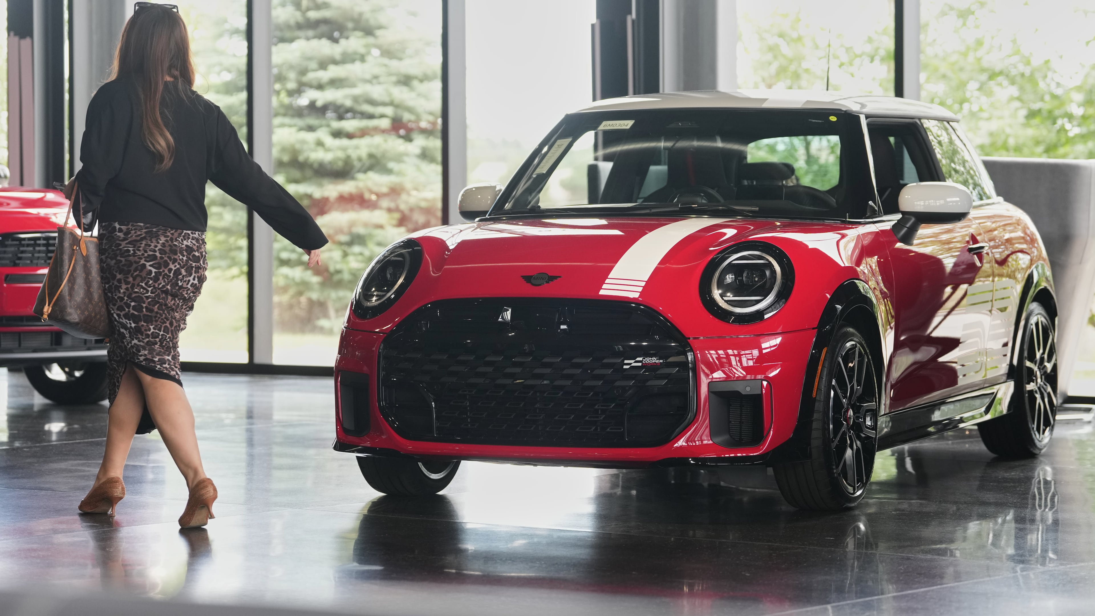 FILE - A shopper passes by an unsold 2026 Cooper S John Cooper Works 1965 Victory Edition hardtop on display in the showroom of a Mini dealership Friday, June 26, 2026, in Highlands Ranch, Colo. (AP Photo/David Zalubowski, File)