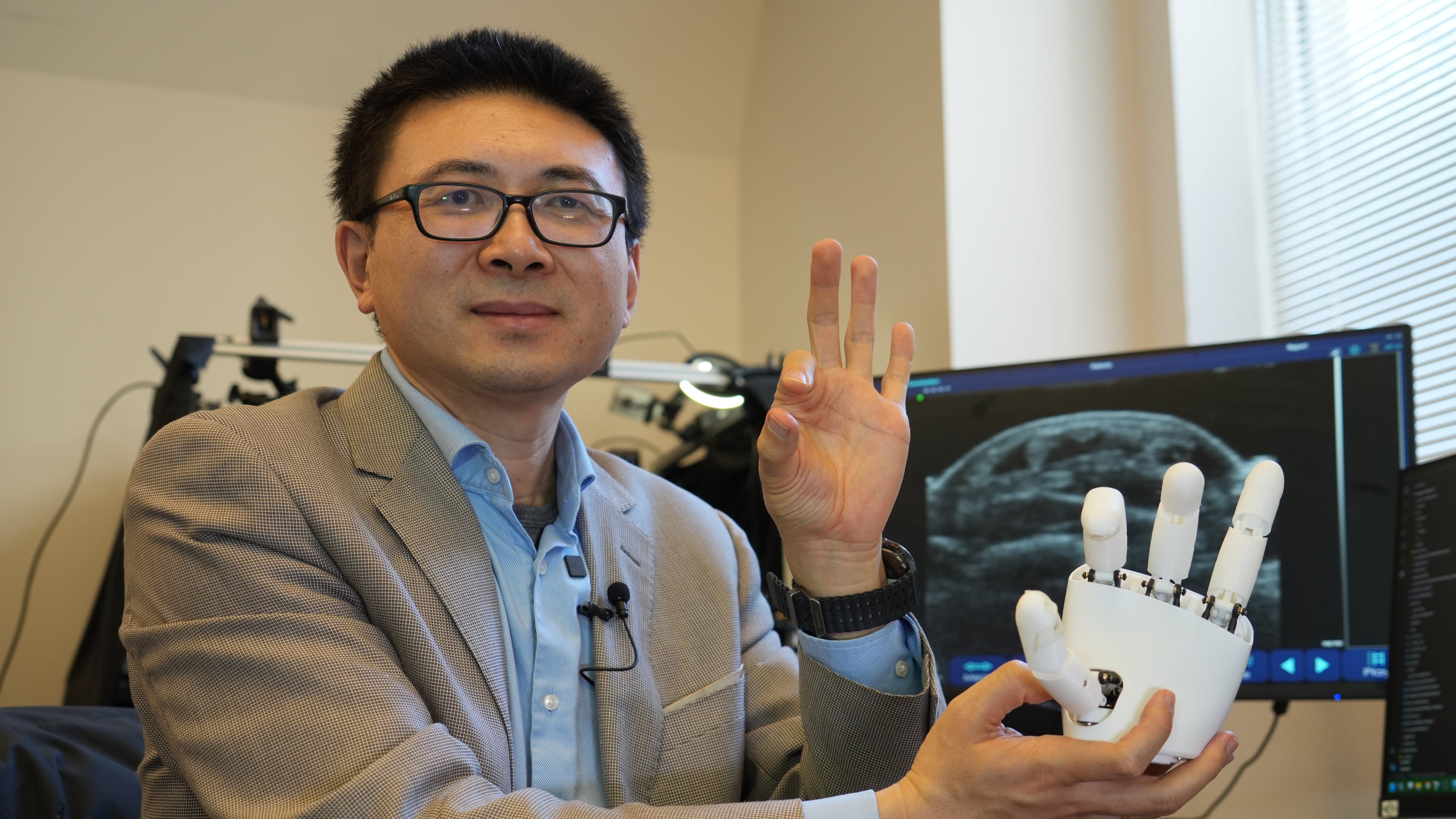 Xuanhe Zhao, professor of mechanical engineering at the Massachusetts Institute of Technology, poses for a portrait with an ultrasound wristband that can help a robotic hand mimic full hand motions in Cambridge, Mass, on Tuesday, April 14, 2026. (AP Photo/Rodrique Ngowi)
