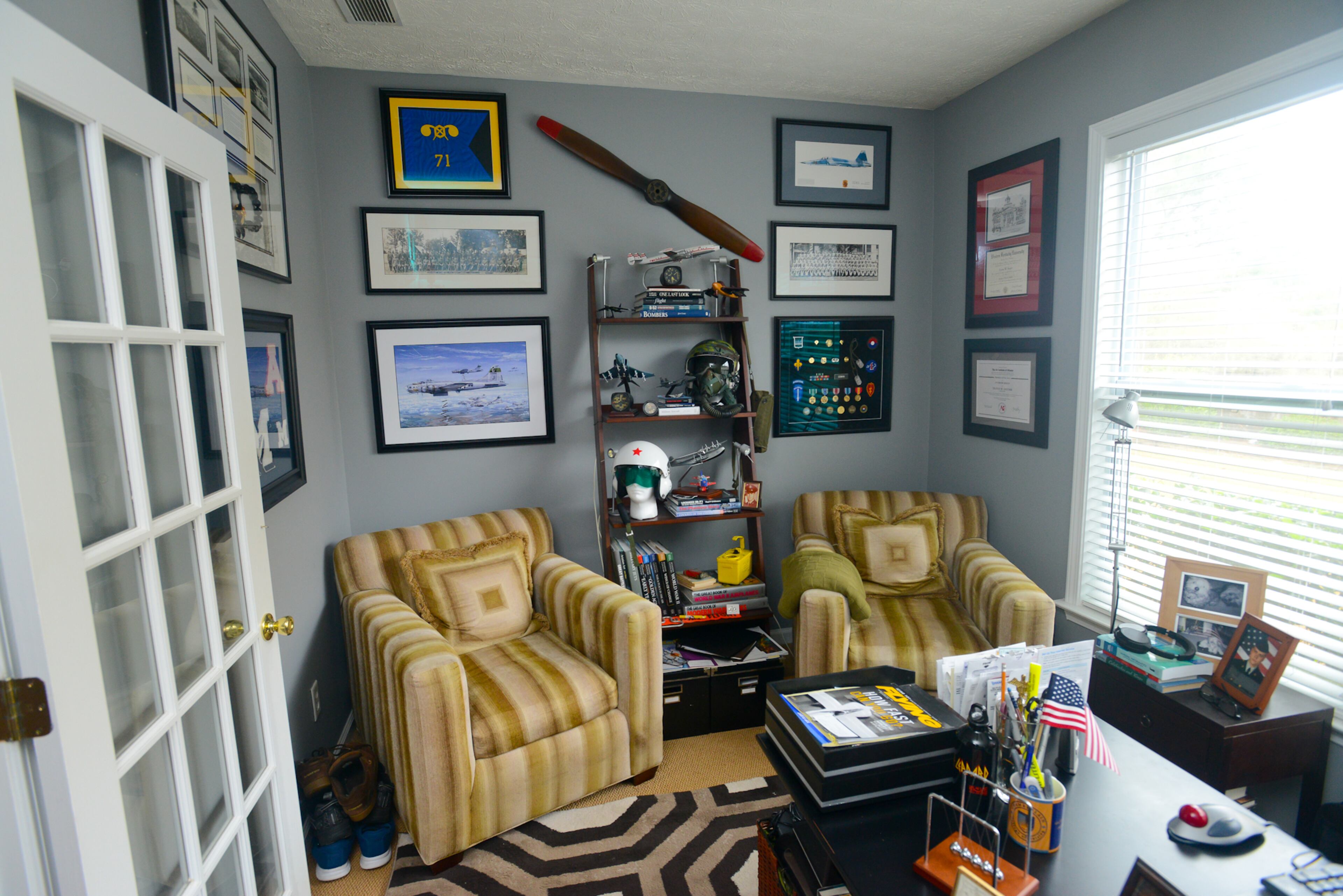 In the home office, striped chairs from Duralee Furniture provide a comfortable perch to view the homeowners' collection of vintage military aviation accessories.