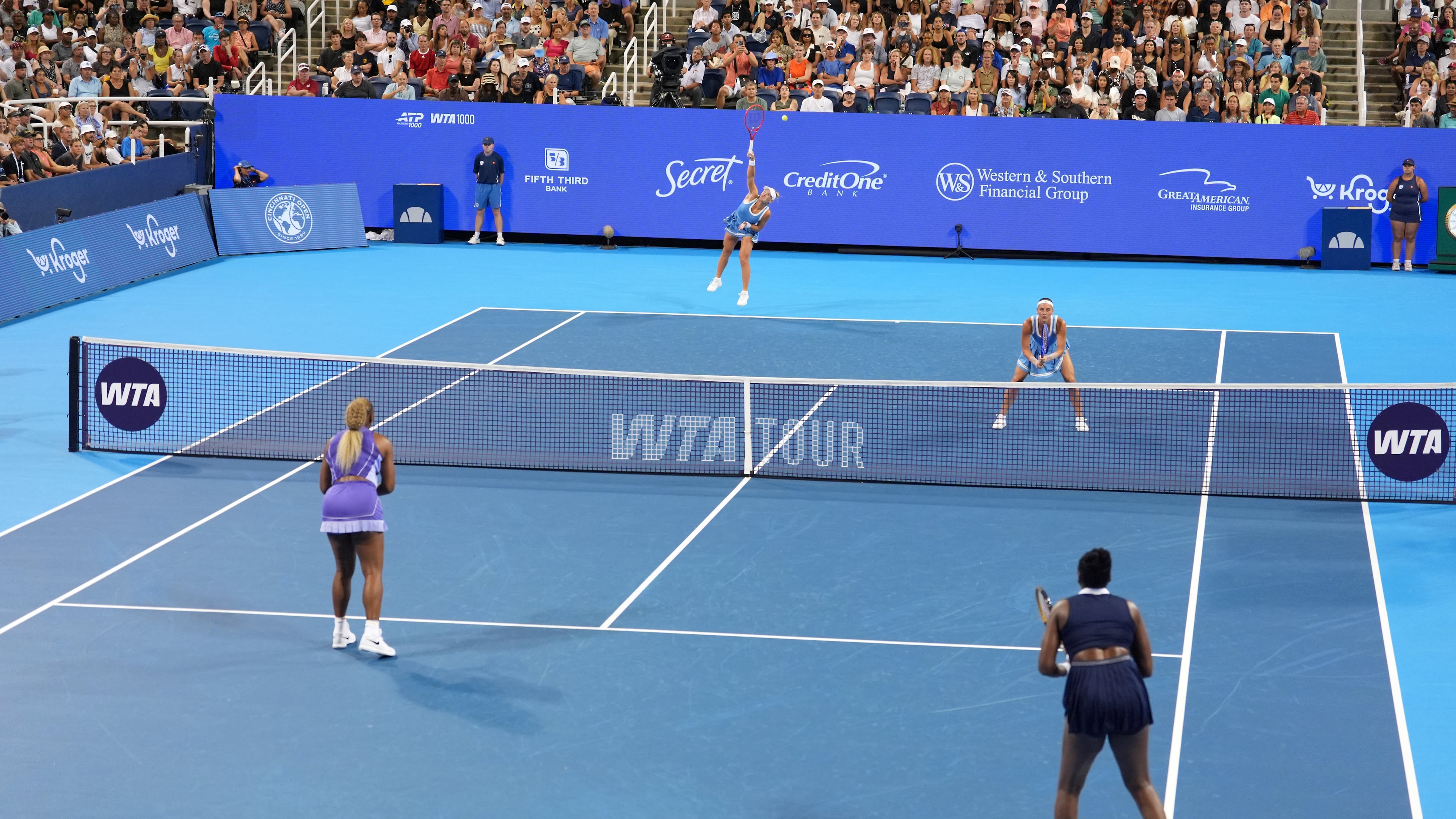 As Peyton Stearns, top right, of the United States, looks on, Marta Kostyuk, top center, of Ukraine, serves against Serena Williams, bottom left, and Venus Williams, bottom right, also of the United States, during a women's doubles match at the Cincinnati Open tennis tournament, Monday, Aug. 17, 2026, in Mason, Ohio. (AP Photo/Kareem Elgazzar)