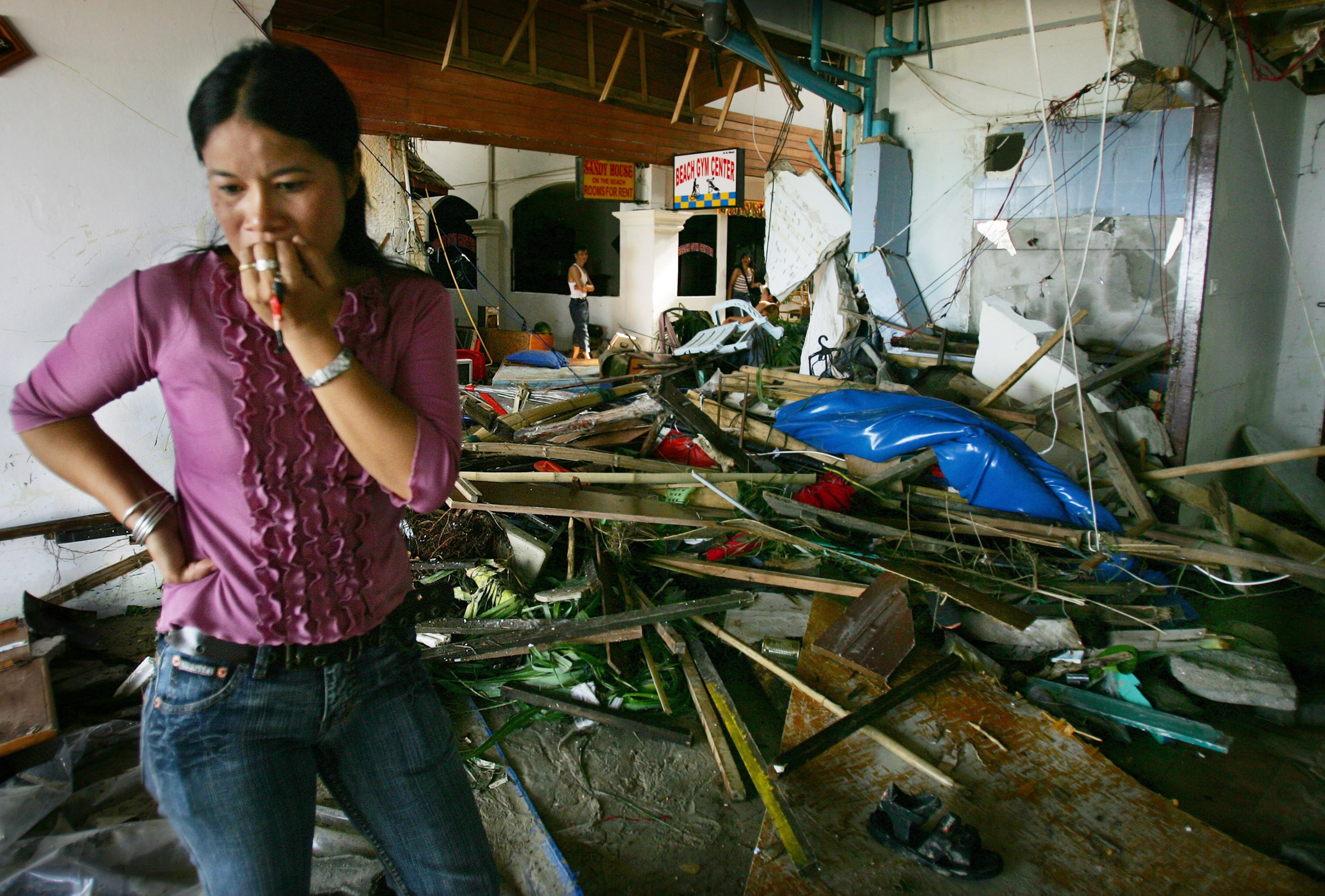 PATONG, THAILAND - DECEMBER 27: A Thai woman walks by the devastation at a hotel along Patong Beach, one of the worst hit provinces December 27, 2004 in Phuket, Thailand. A tsunami, caused by an earthquake estimated to be 9.0 in magnitude, is responsible for killing thousands of people throughout Asia. (Photo by Paula Bronstein/Getty Images)