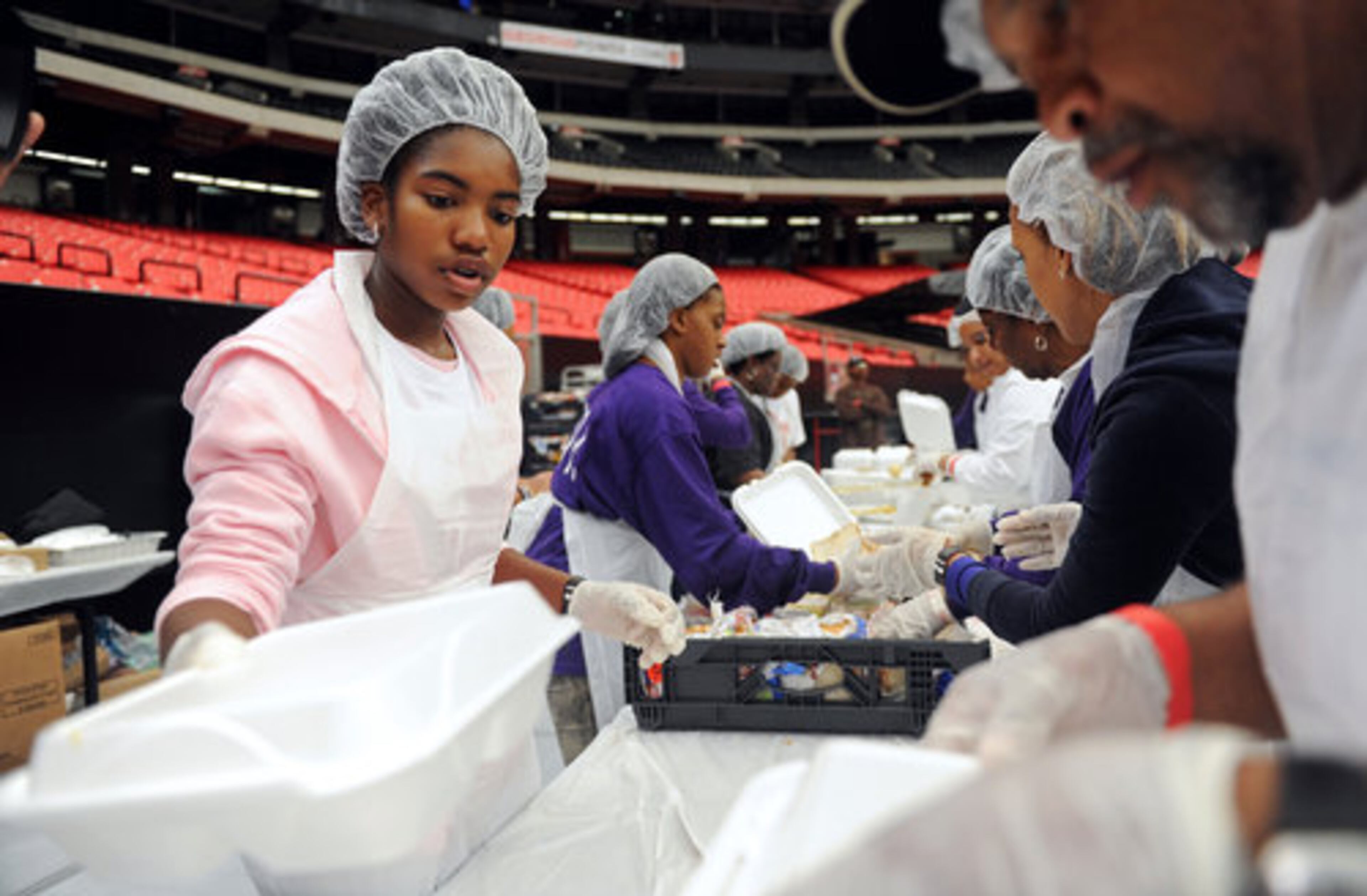Volunteer Amira Williams (in pink), 12, helps prepare boxed meals.