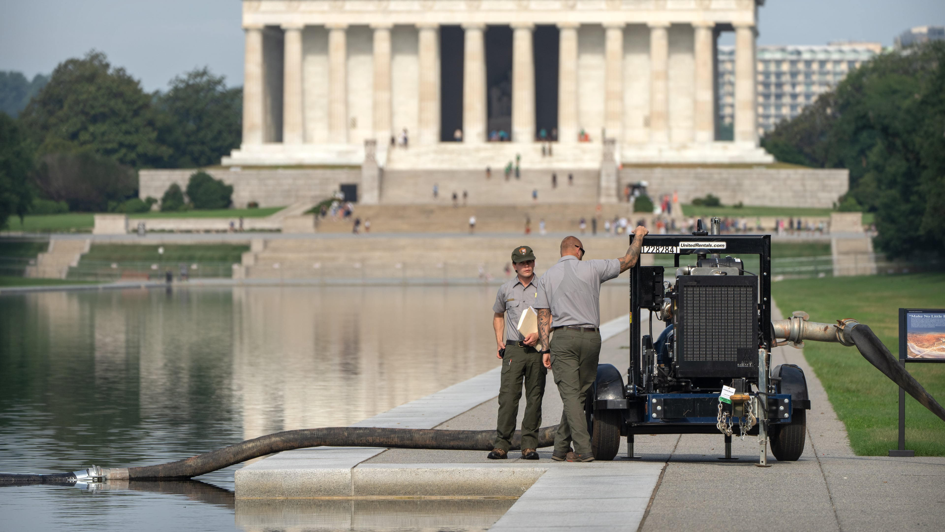 National Park Service workers stand near a pump placed next to the Lincoln Memorial Reflecting Pool, Friday, July 10, 2026, in Washington. (AP Photo/Mark Schiefelbein)