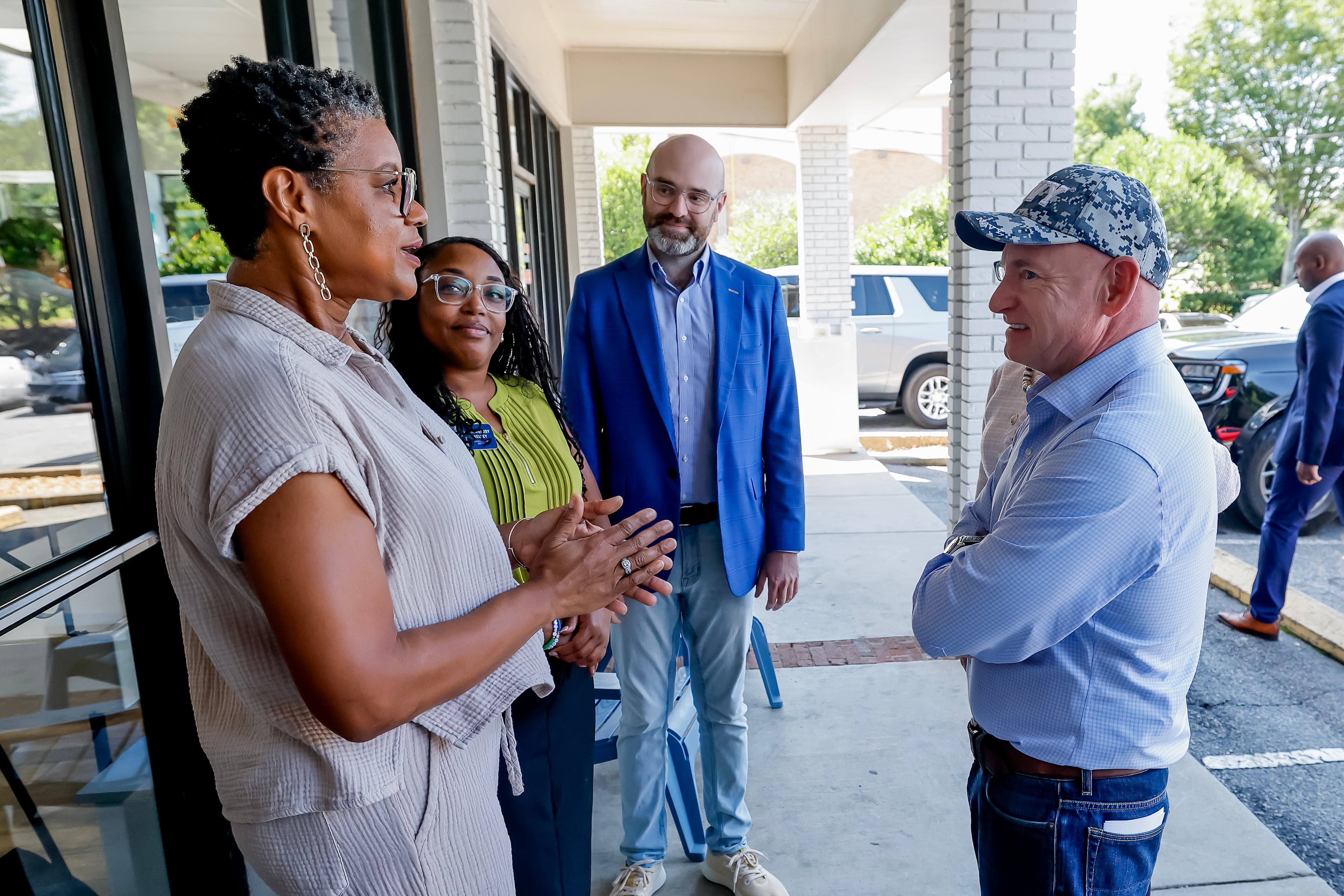 From left, Laundry Lounge owner Sherwin Clemons, Sandy Springs councilwoman Melody Kelley and Democratic nominee for lieutenant governor Josh McLaurin talk with U.S. Sen. Mark Kelly during a campaign stop in Sandy Springs on Wednesday, Aug. 19, 2026. (Erik S. Lesser for the AJC)