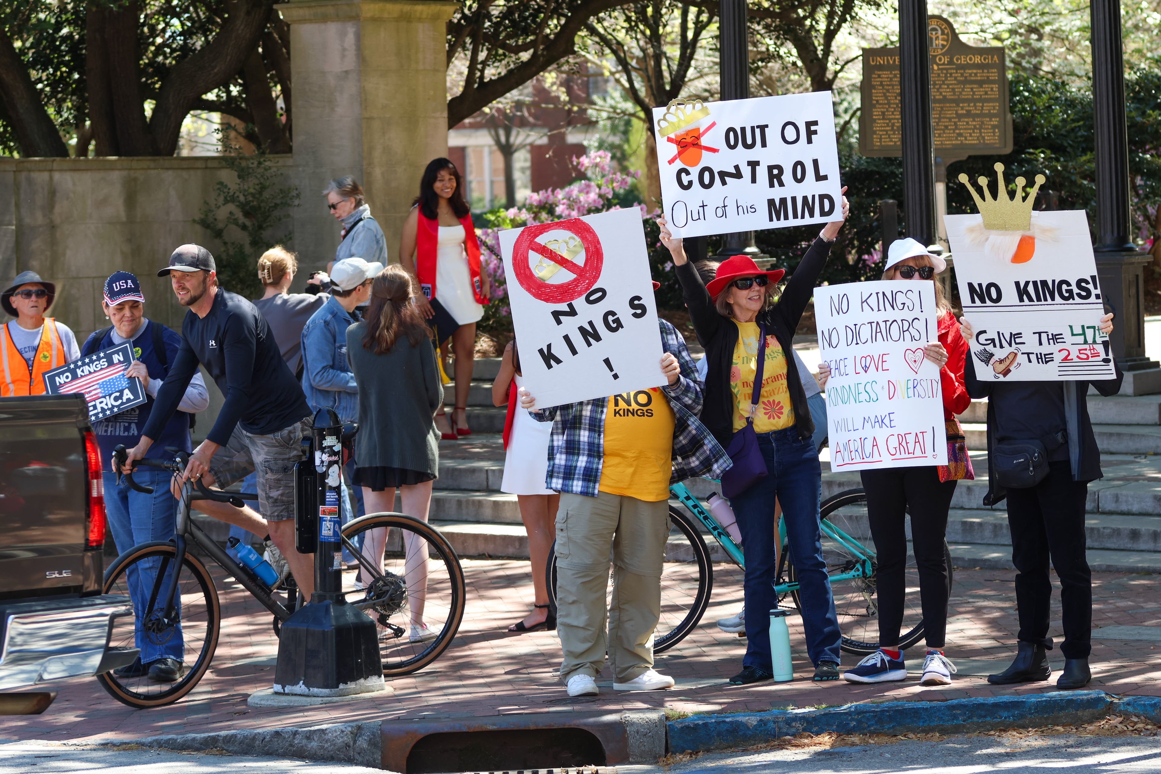 People hold signs at UGA’s Arch in Athens on Saturday, March 28, 2026. Protesters gathered in 10 different locations around Georgia’s Congressional District 10, leading up to a “Democracy Fair” at Athens’ Bishop Park as part of a nationwide day of “No Kings” demonstrations. Organizers estimate that a few thousand people participated, many of them first-time protesters. (C.J. Bartunek for the AJC)