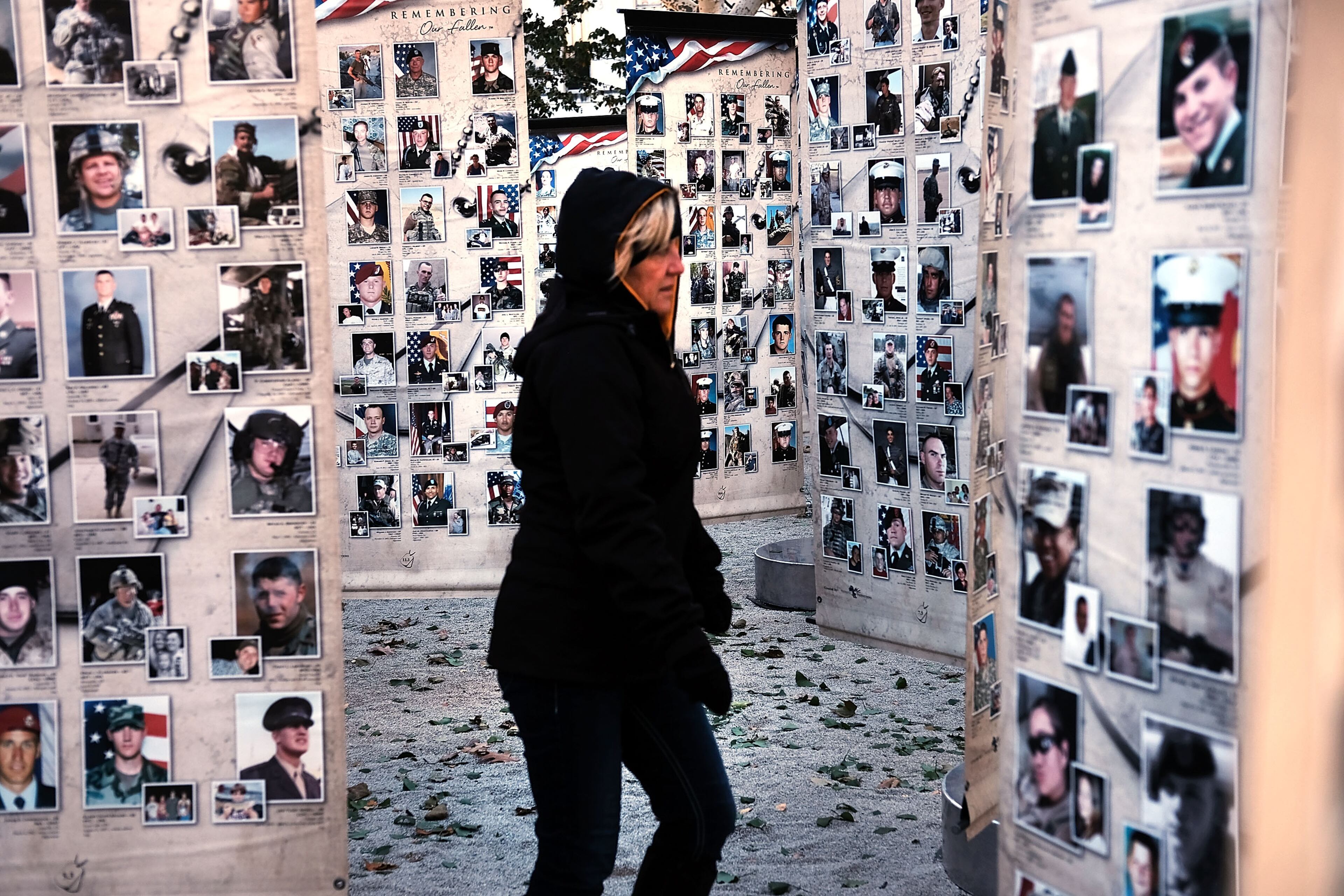 NEW YORK, NY - NOVEMBER 11: A woman looks at pictures of fallen soldiers at Madison Square Park before the start of the Veterans Day Parade on November 11, 2017 in New York City. The largest Veterans Day event in the nation, this year's parade features thousands of marchers, including military units, civic and youth groups, businesses and high school bands from across the country and veterans of all eras. The U.S. Air Force is this year's featured service and the grand marshal is space pioneer Buzz Aldrin. (Photo by Spencer Platt/Getty Images)