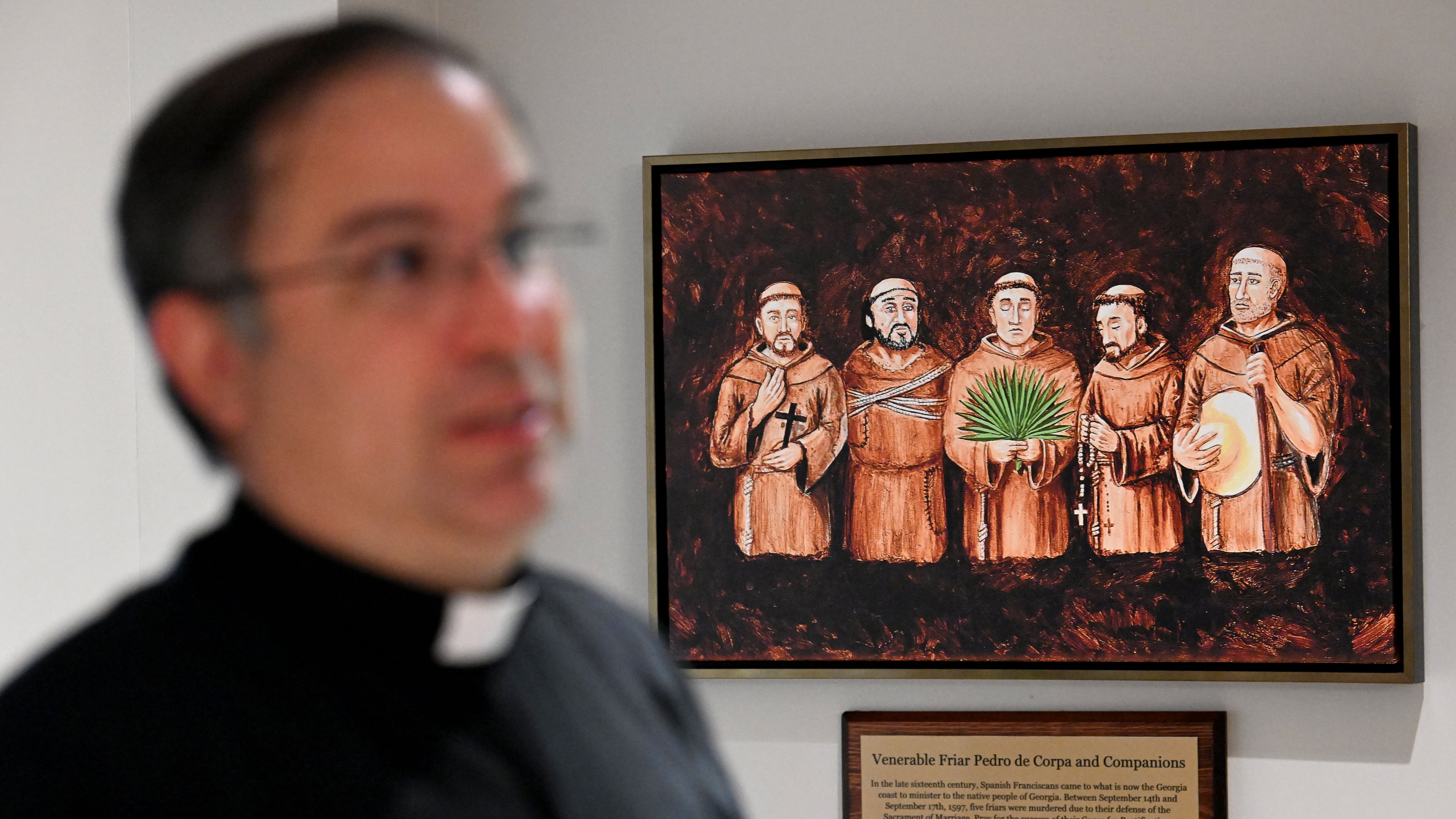 Father Pablo Migone, pastor at Corpus Christi Catholic Church, shows a painting of the Georgia Martyrs. The five friars' beatification will take place in Savannah on Oct. 31. (Hyosub Shin/AJC)