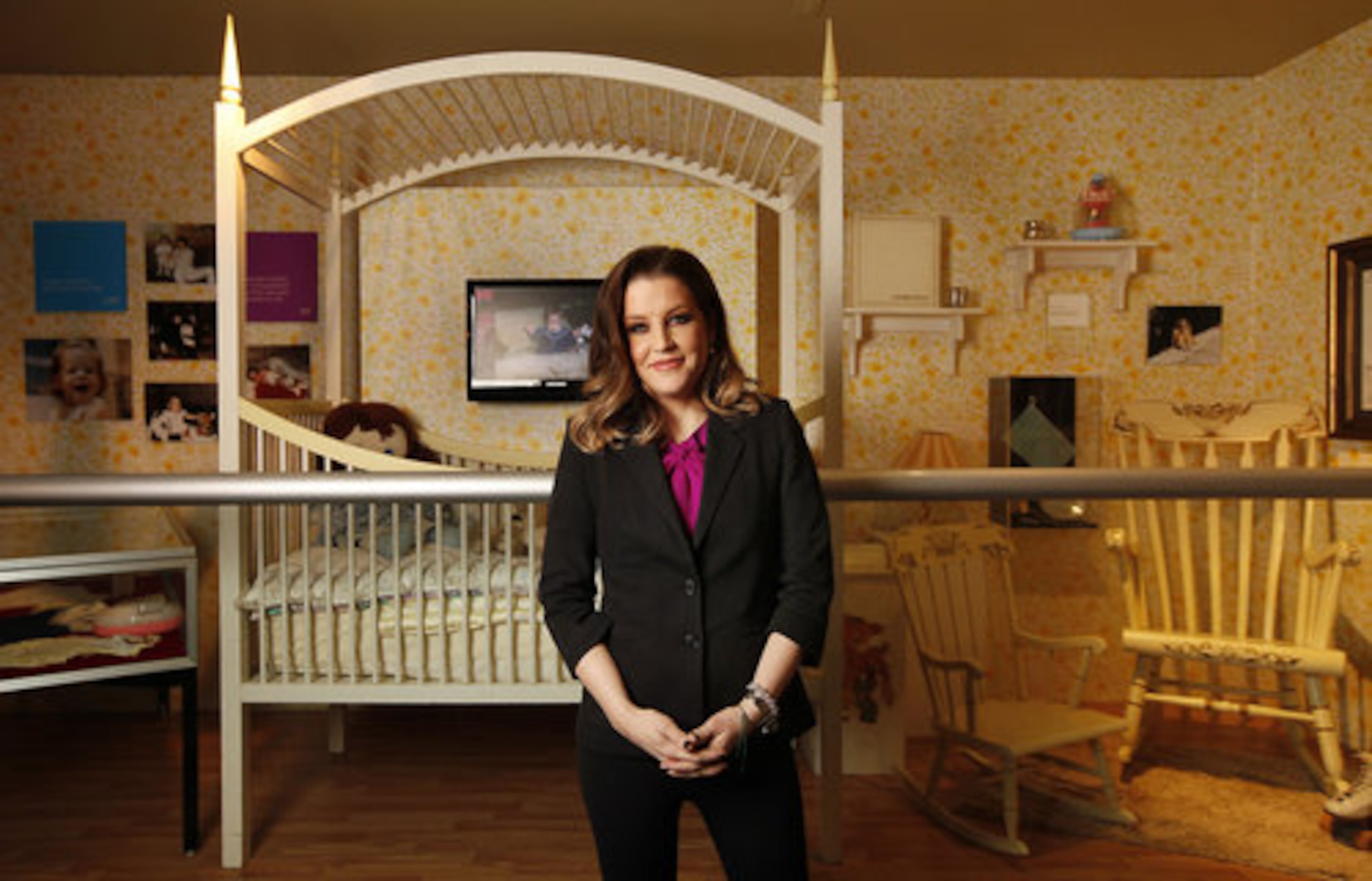 Lisa Marie Presley poses in front of the exhibit depicting her childhood room at Graceland.