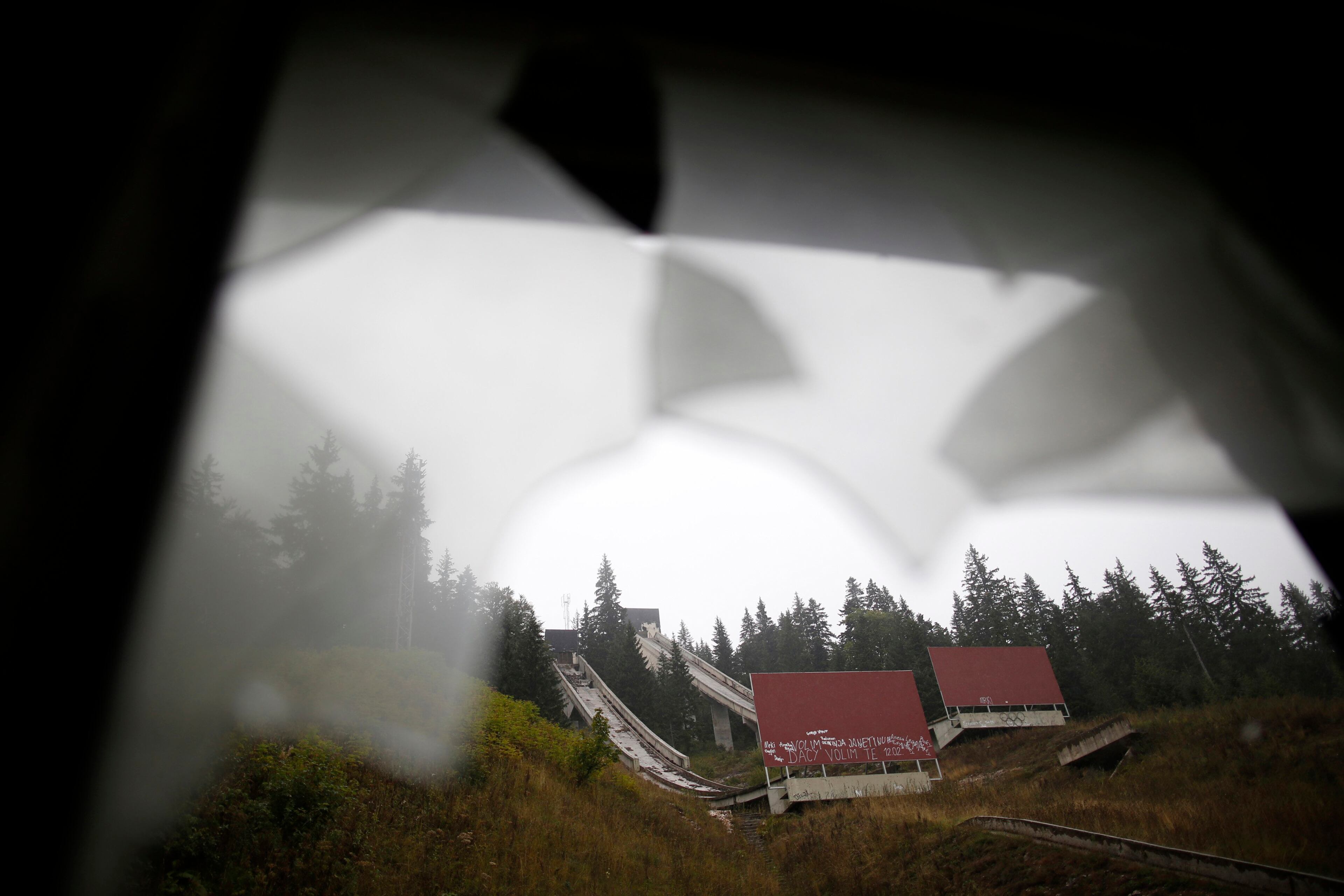 The disused ski jump from the Sarajevo 1984 Winter Olympics is seen through broken windows on Mount Igman, near Saravejo September 19, 2013. Abandoned and left to crumble into oblivion, most of the 1984 Winter Olympic venues in Bosnia's capital Sarajavo have been reduced to rubble by neglect as much as the 1990s conflict that tore apart the former Yugoslavia. The bobsleigh and luge track at Mount Trebevic, the Mount Igman ski jumping course and accompanying objects are now decomposing into obscurity. The bobsleigh and luge track, which was also used for World Cup competitions after the Olympics, became a Bosnian-Serb artillery stronghold during the war and is nowadays a target of frequent vandalism. The clock is now ticking towards the 2014 Winter Olympics, with October 29 marking 100 days to the opening of the Games in the Russian city of Sochi. Picture taken on September 19, 2013. REUTERS/Dado Ruvic