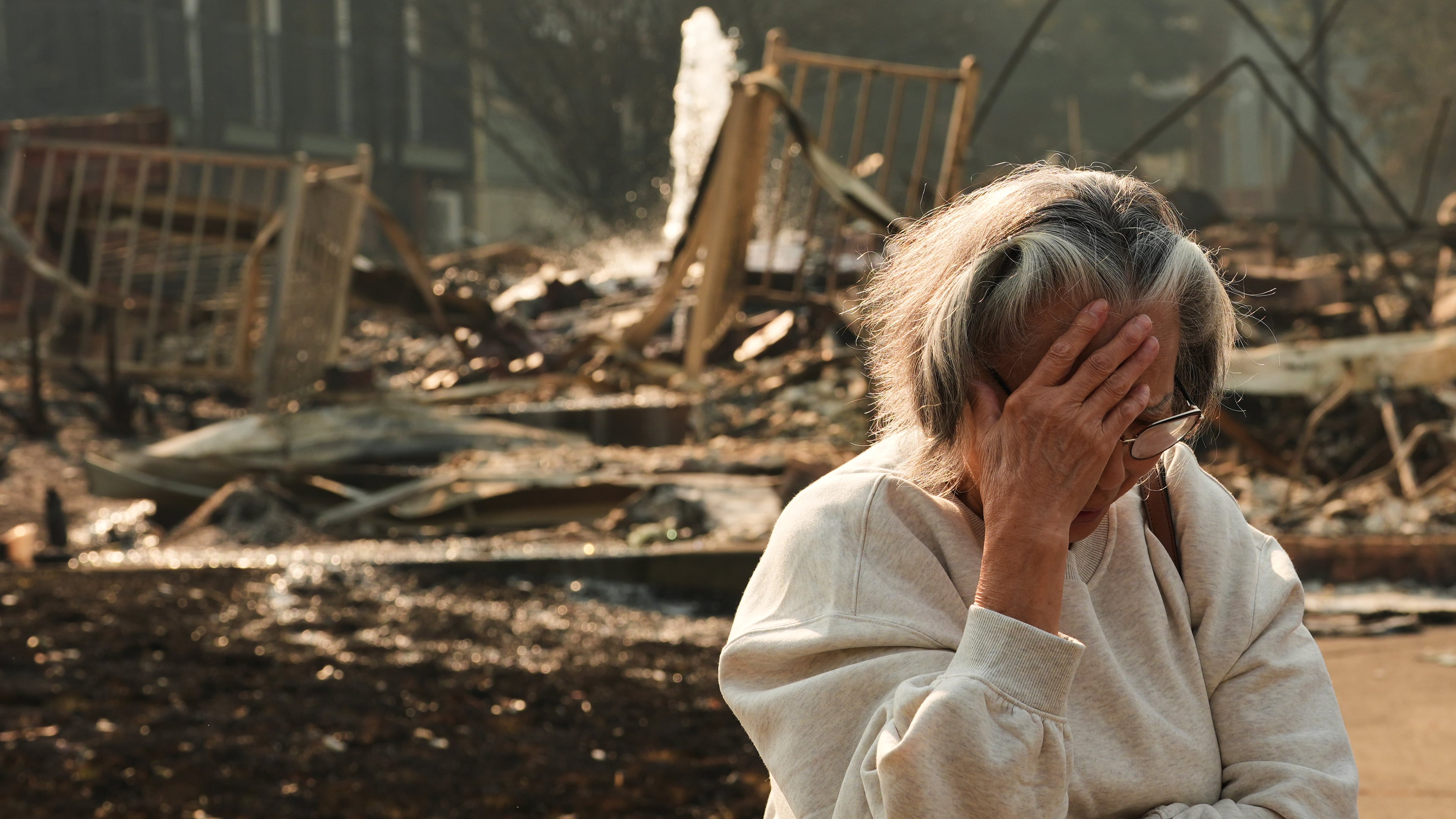 Miriam Sim, 76, reacts while talking about her neighborhood largely burning to the ground after a wildfire hit the northern part of Spokane, Wash., Monday, Aug. 3, 2026. (AP Photo/Lindsey Wasson)
