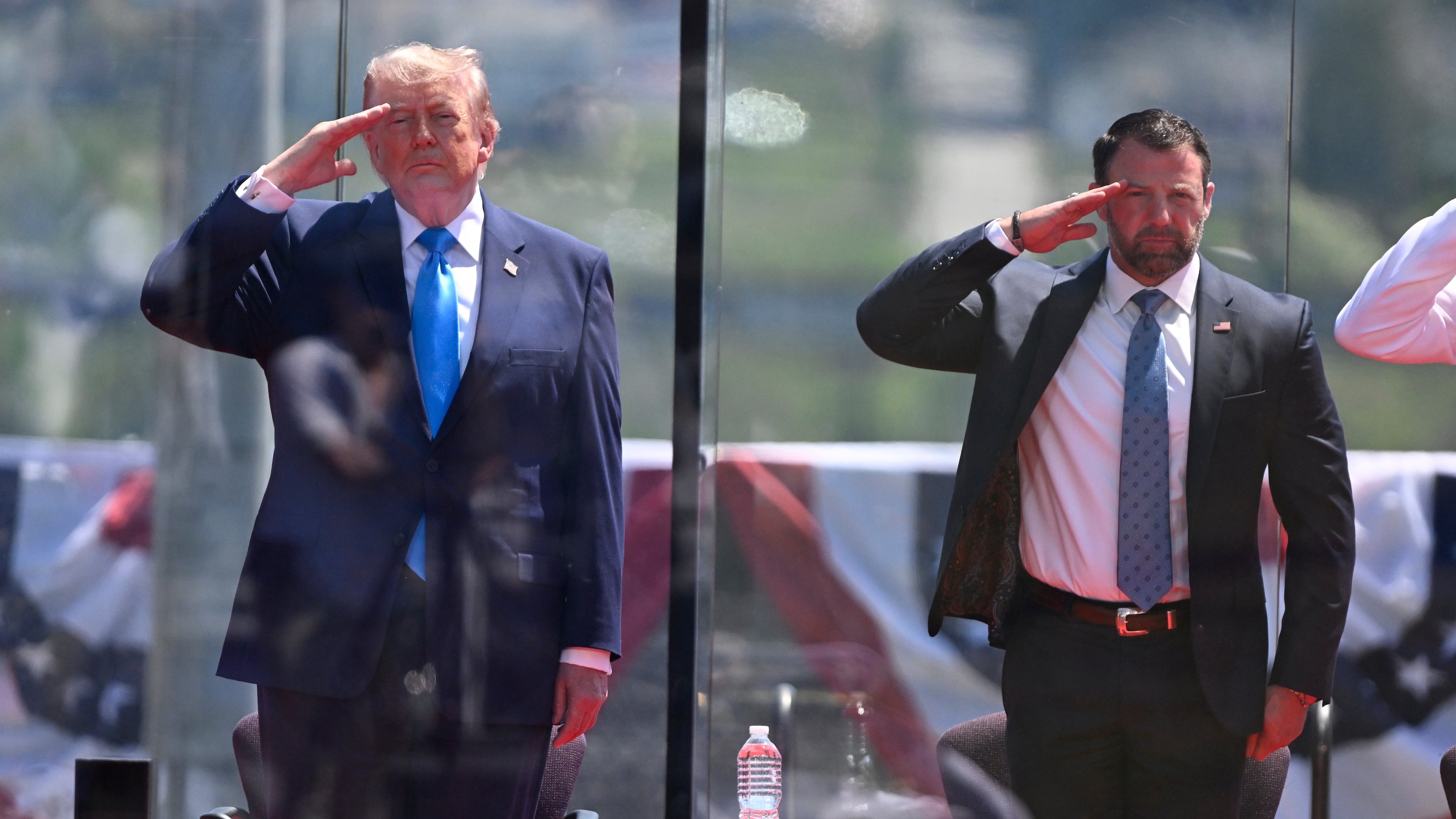 President Donald Trump, left, and Secretary of Homeland Security Markwayne Mullin, right, saluting at the start of the commencement ceremony at the U.S. Coast Guard Academy in New London, Conn., Wednesday, May 20, 2026. (AP Photo/Jessica Hill)